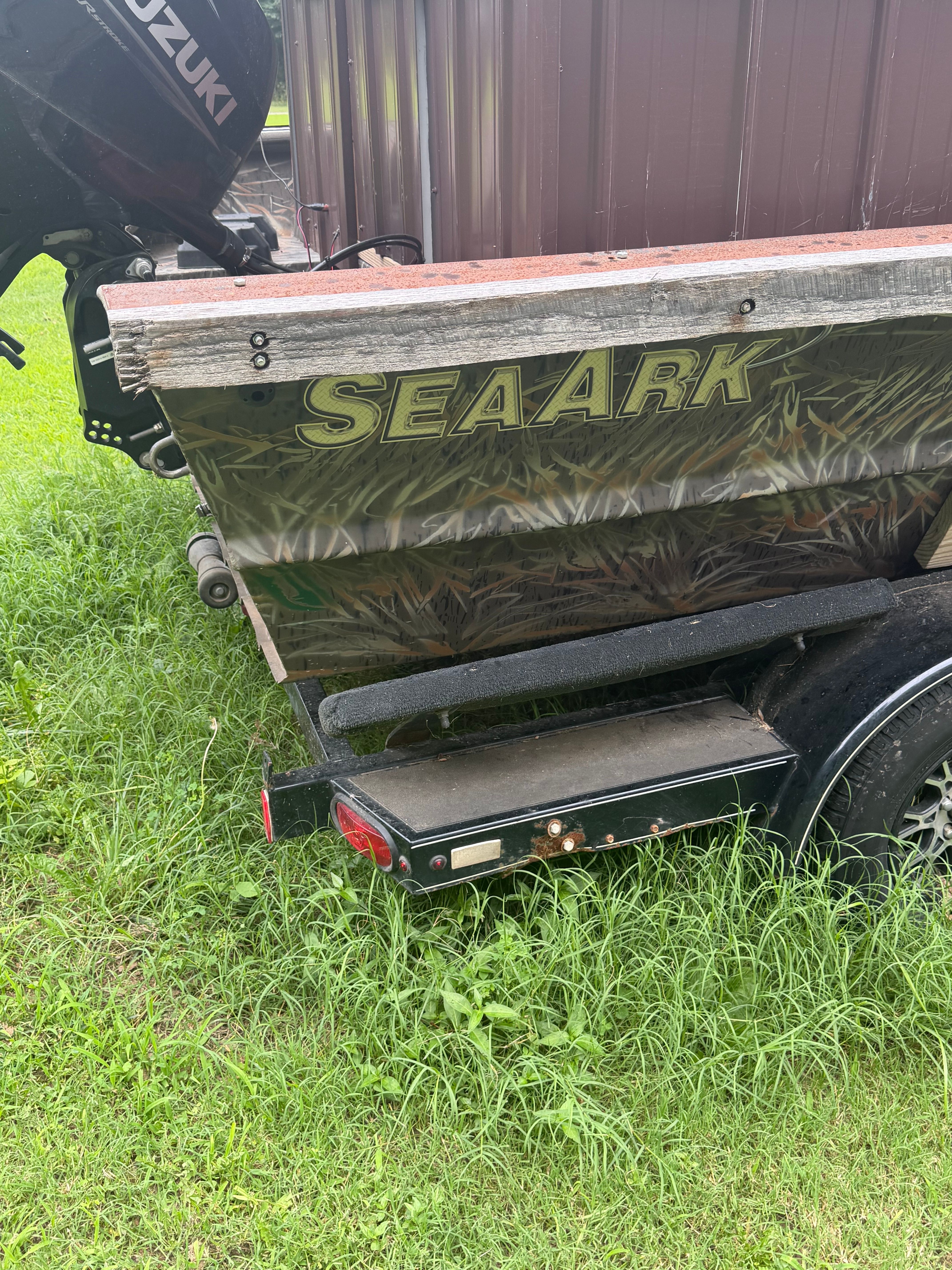 SeaArk 24-foot boat from 2023 parked on a trailer in the grass.