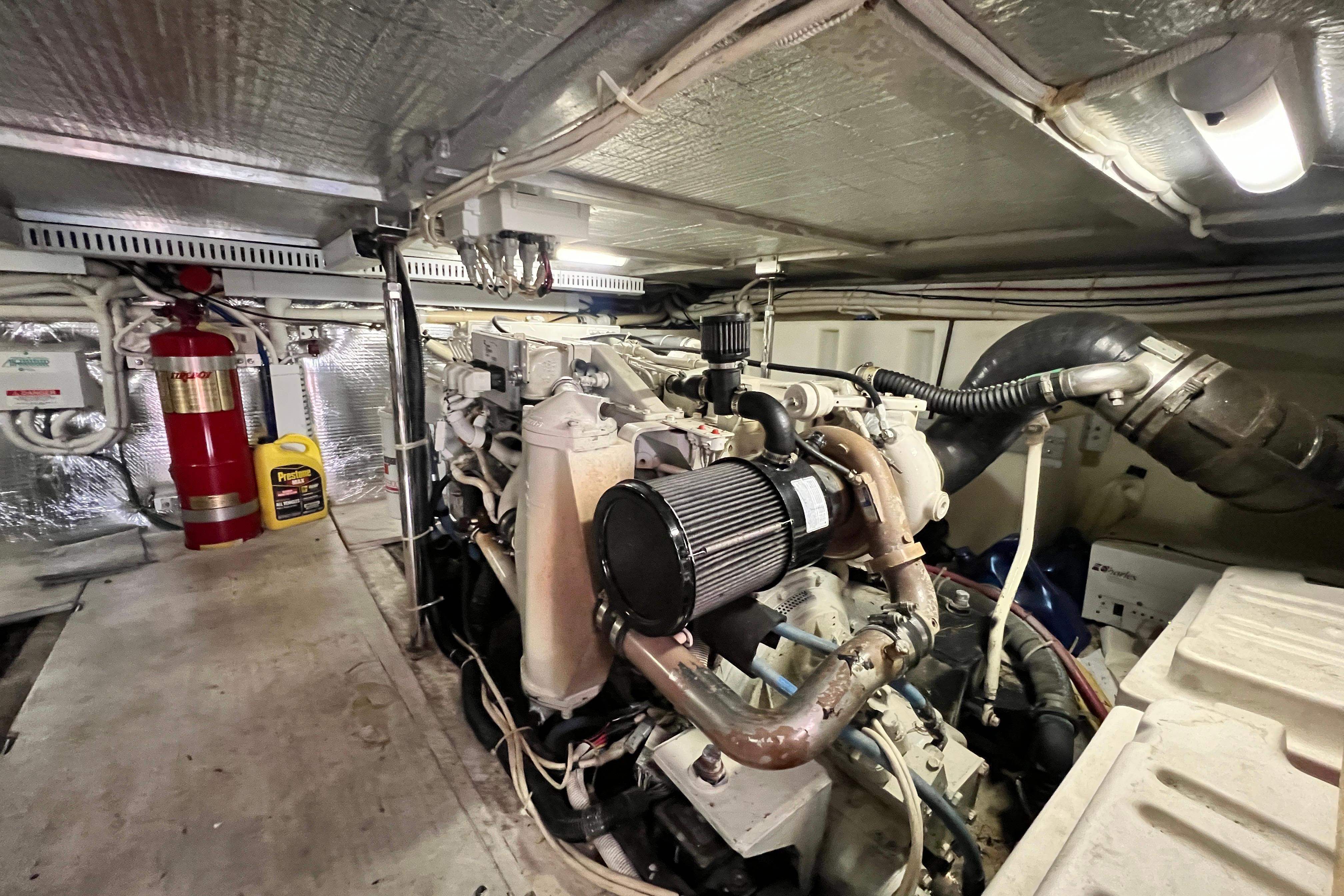 Engine room of 2003 Carver 450 Voyager Pilothouse with visible machinery and fire extinguisher.