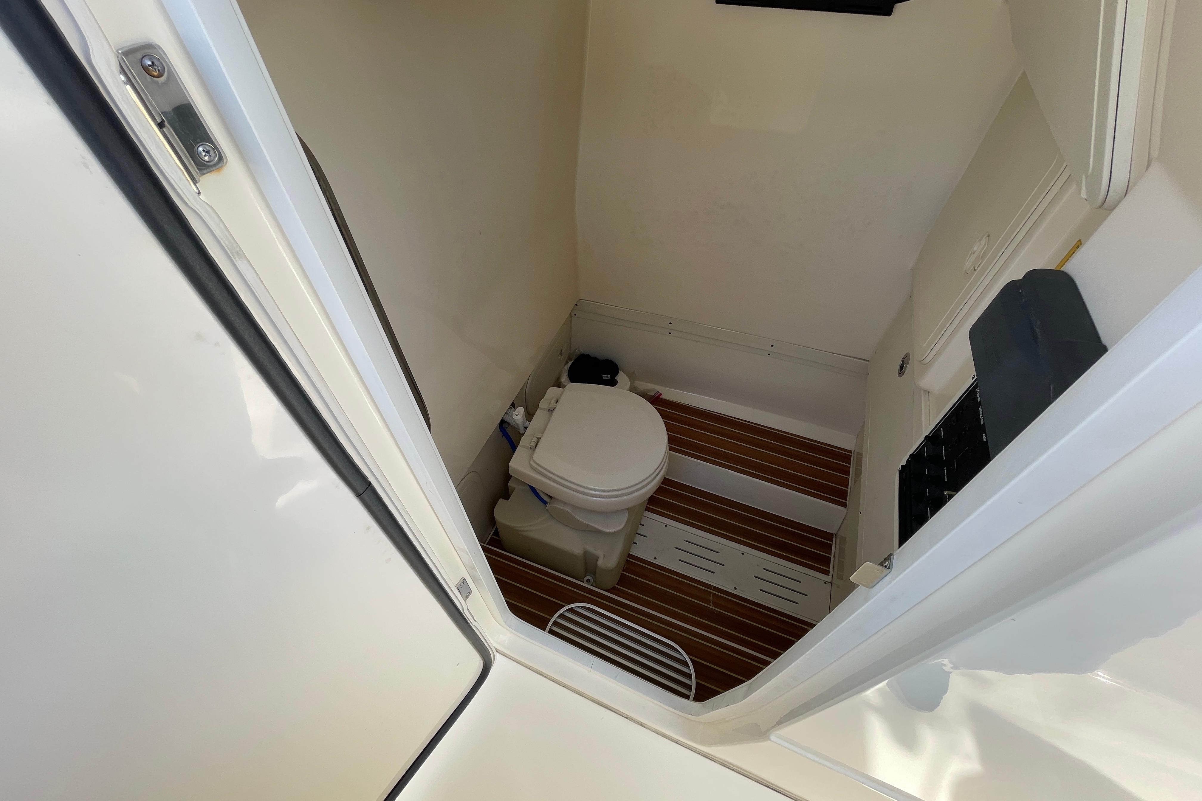 2020 Scout 255 LXF boat interior with compact marine toilet and wooden flooring.