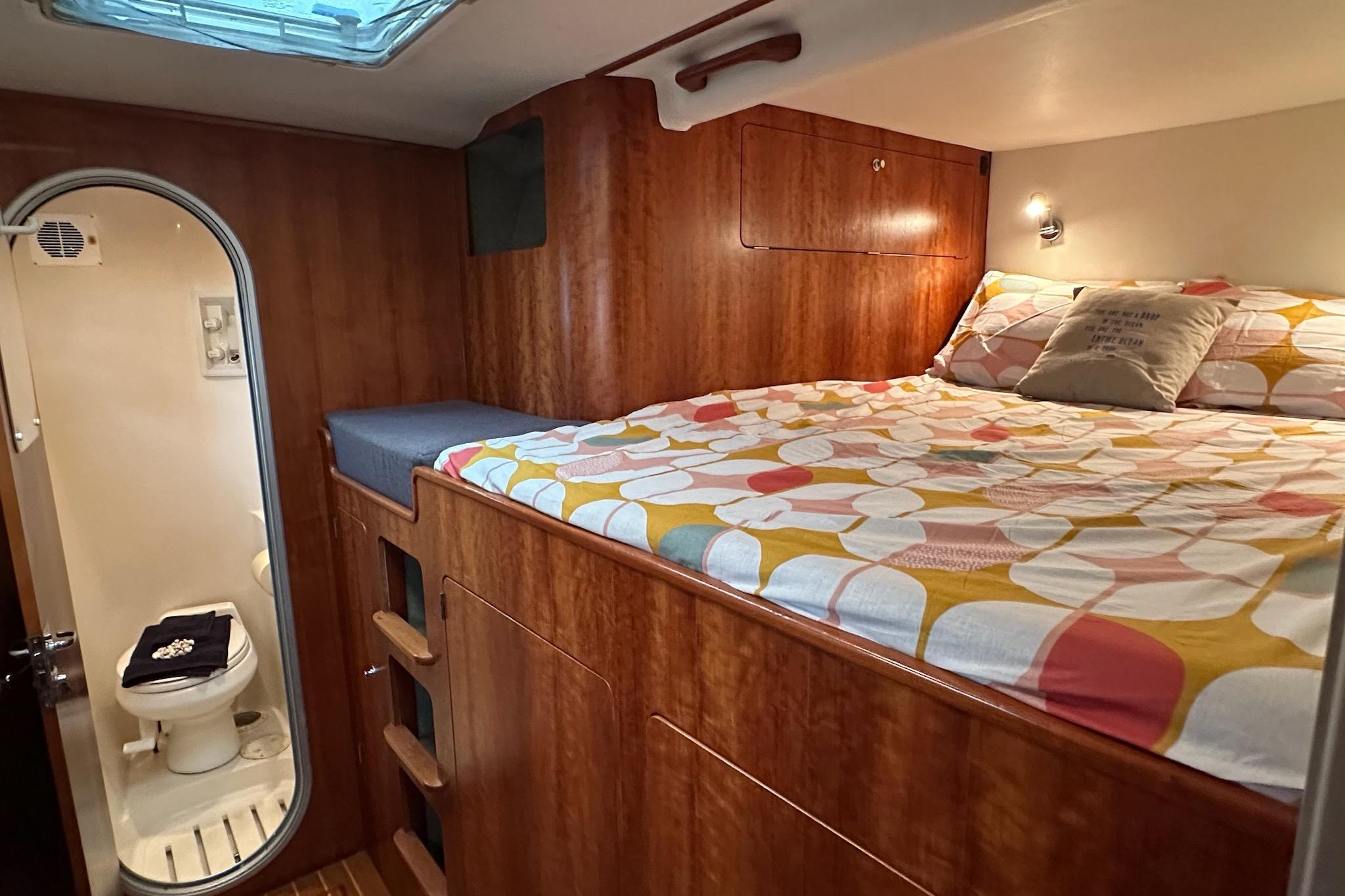 Cozy 2002 PDQ Antares cabin with bed, colorful bedding, and compact bathroom.