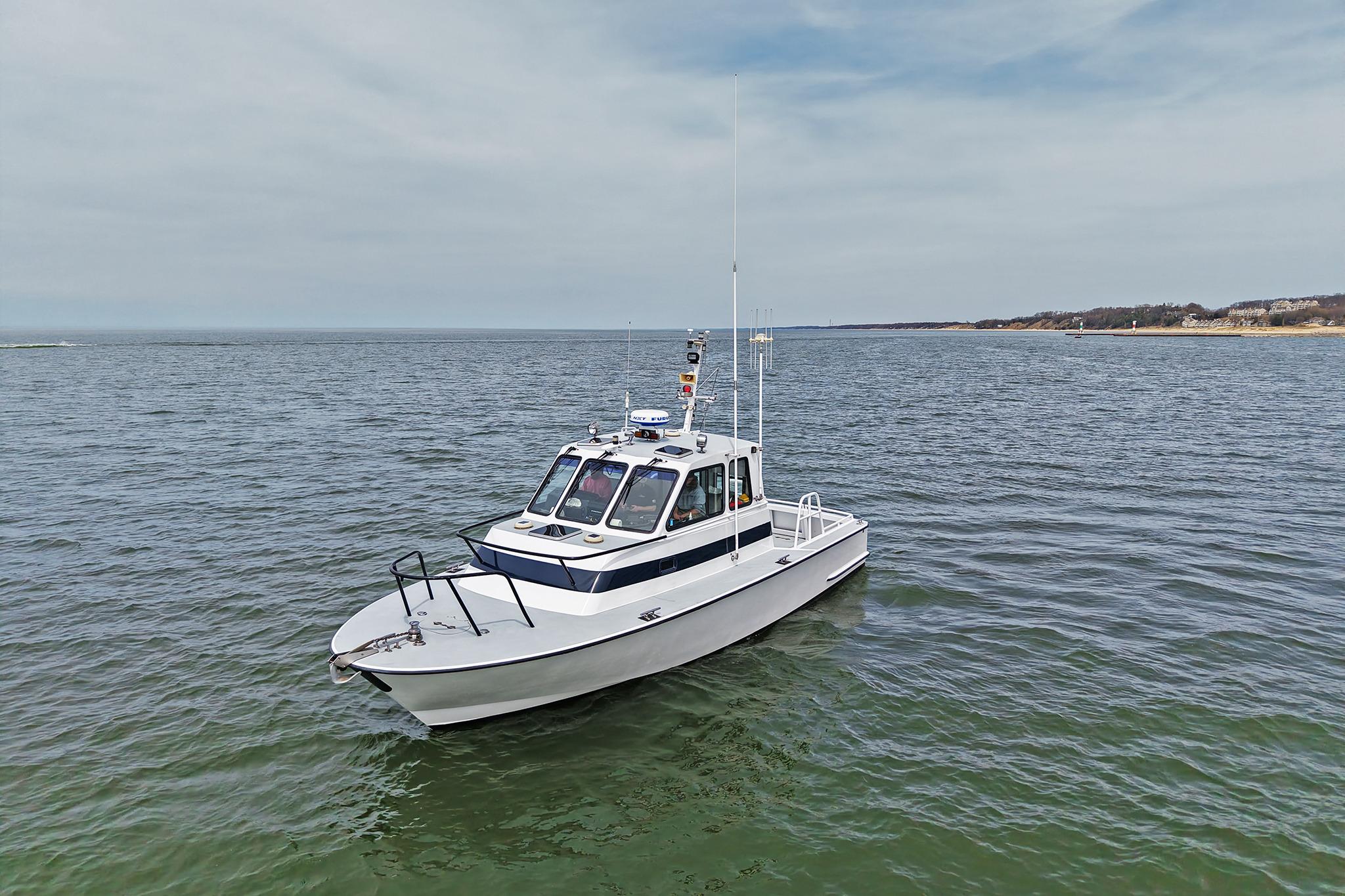 1990 Boston Whaler 36 Defiance boat on calm water under a cloudy sky.