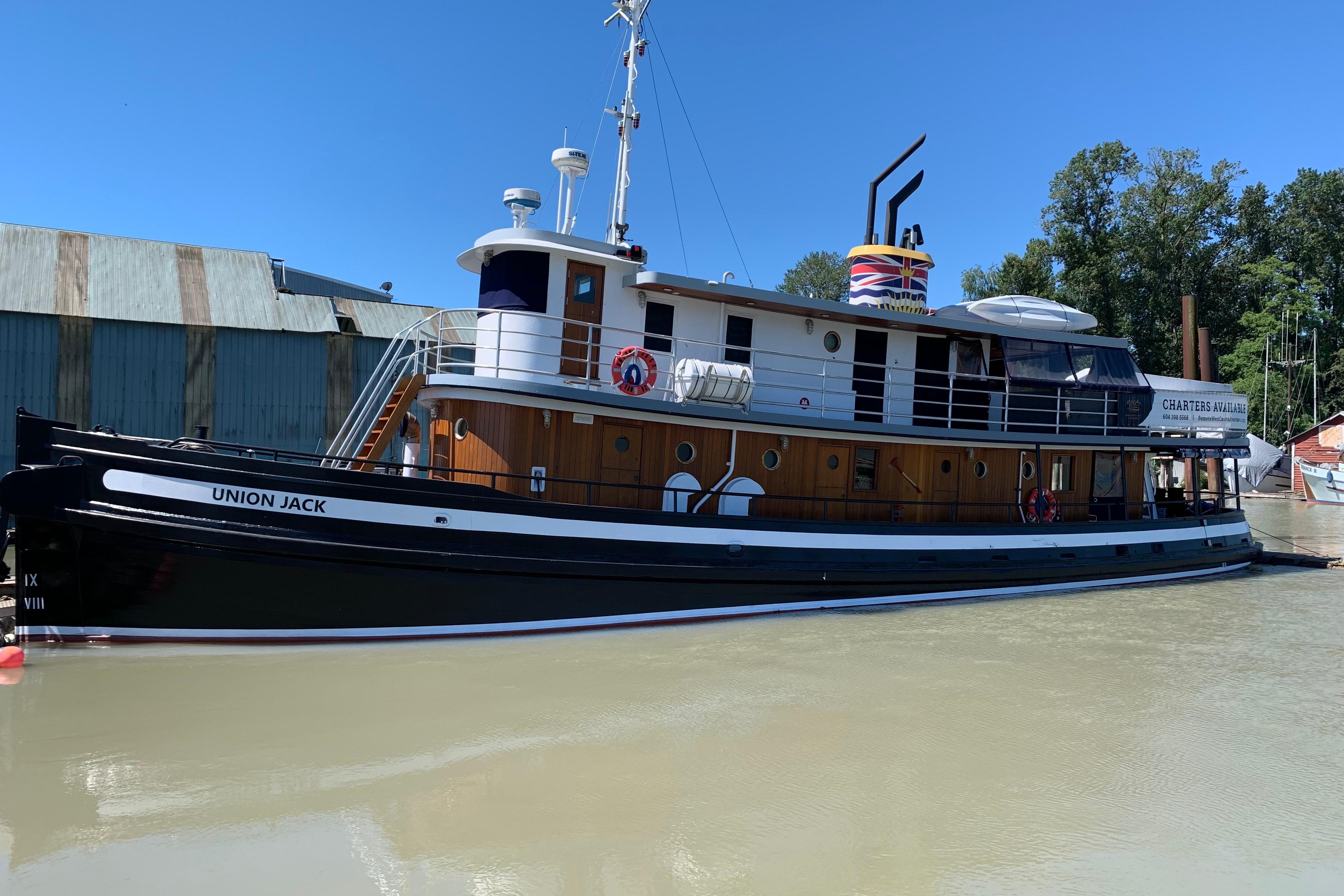 Historic 1941 McKenzie Barge & Derrick Co. Ltd tugboat "Union Jack" docked by a riverside.