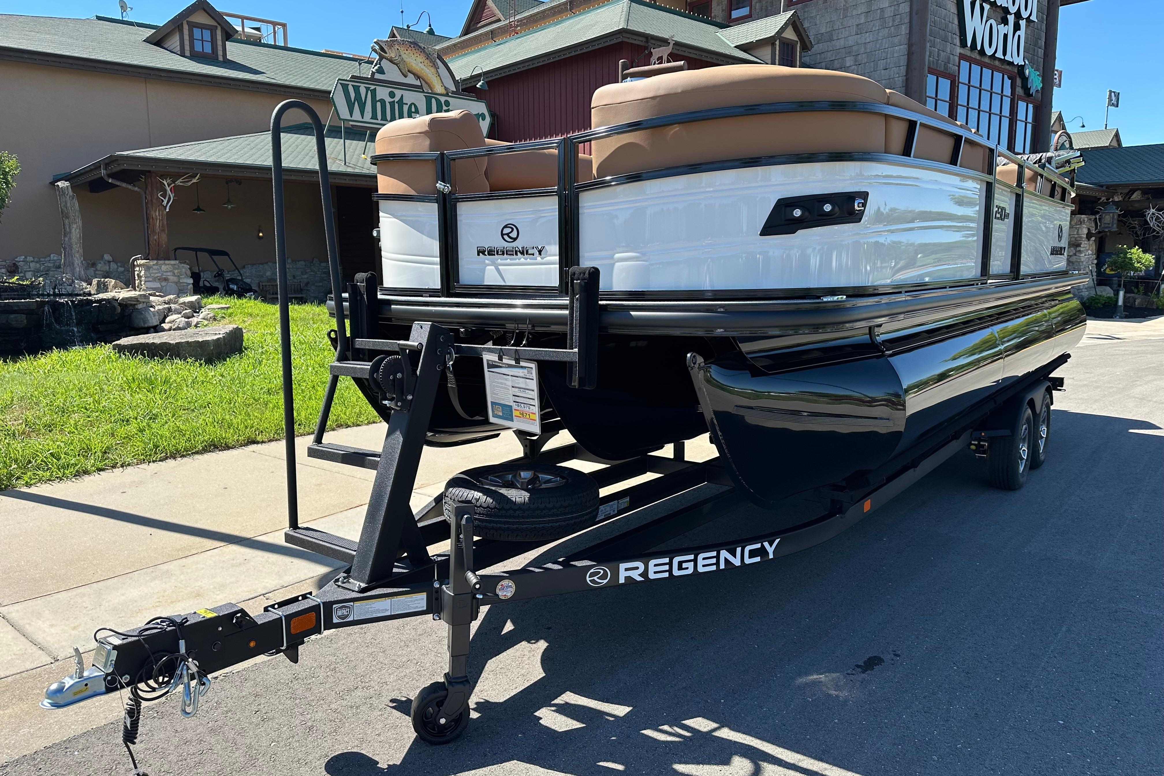 2026 Regency 230 DL pontoon boat on trailer, parked outside a rustic building.