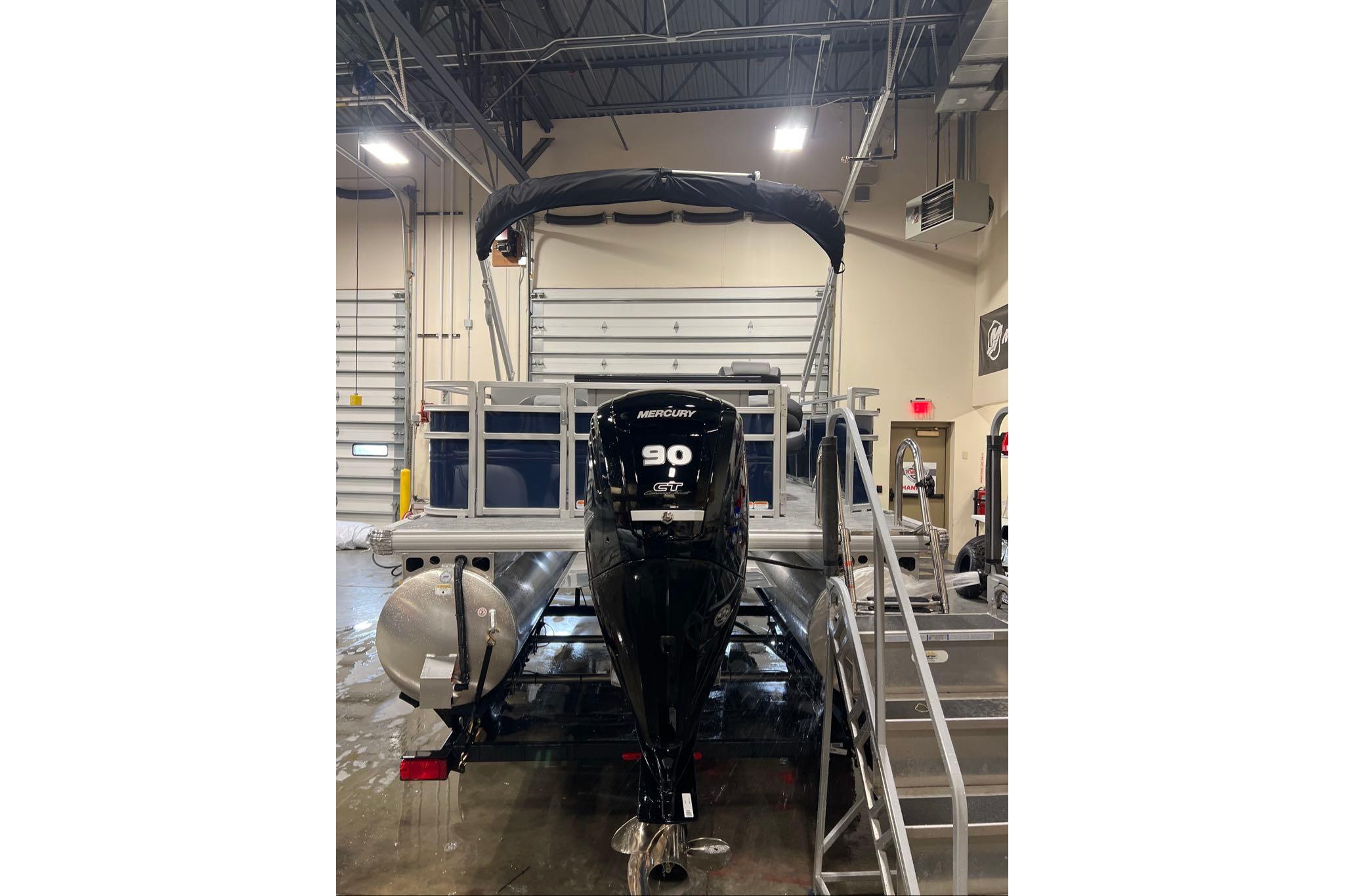 2026 Sun Tracker SportFish 20 DLX pontoon boat in a garage setting.