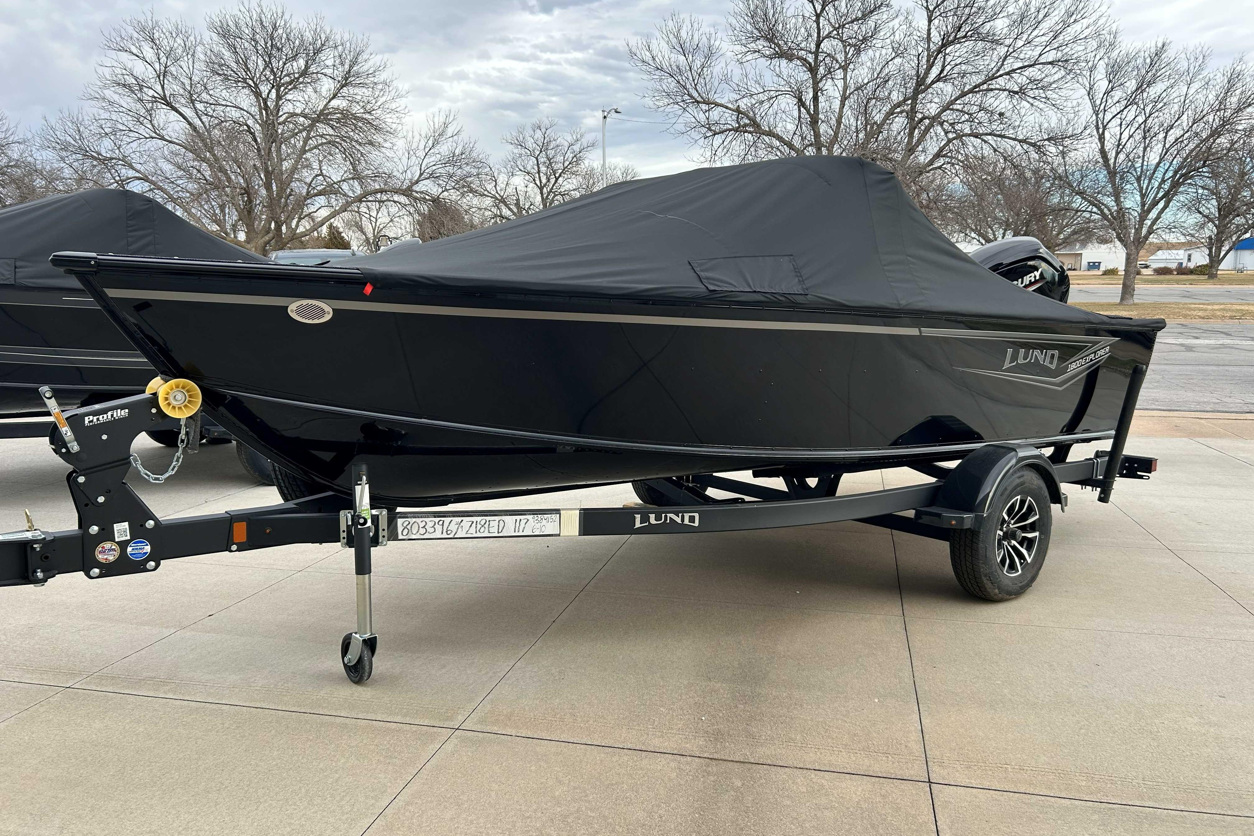 2026 Lund 1800 Explorer Sport boat with cover on trailer, parked outdoors.