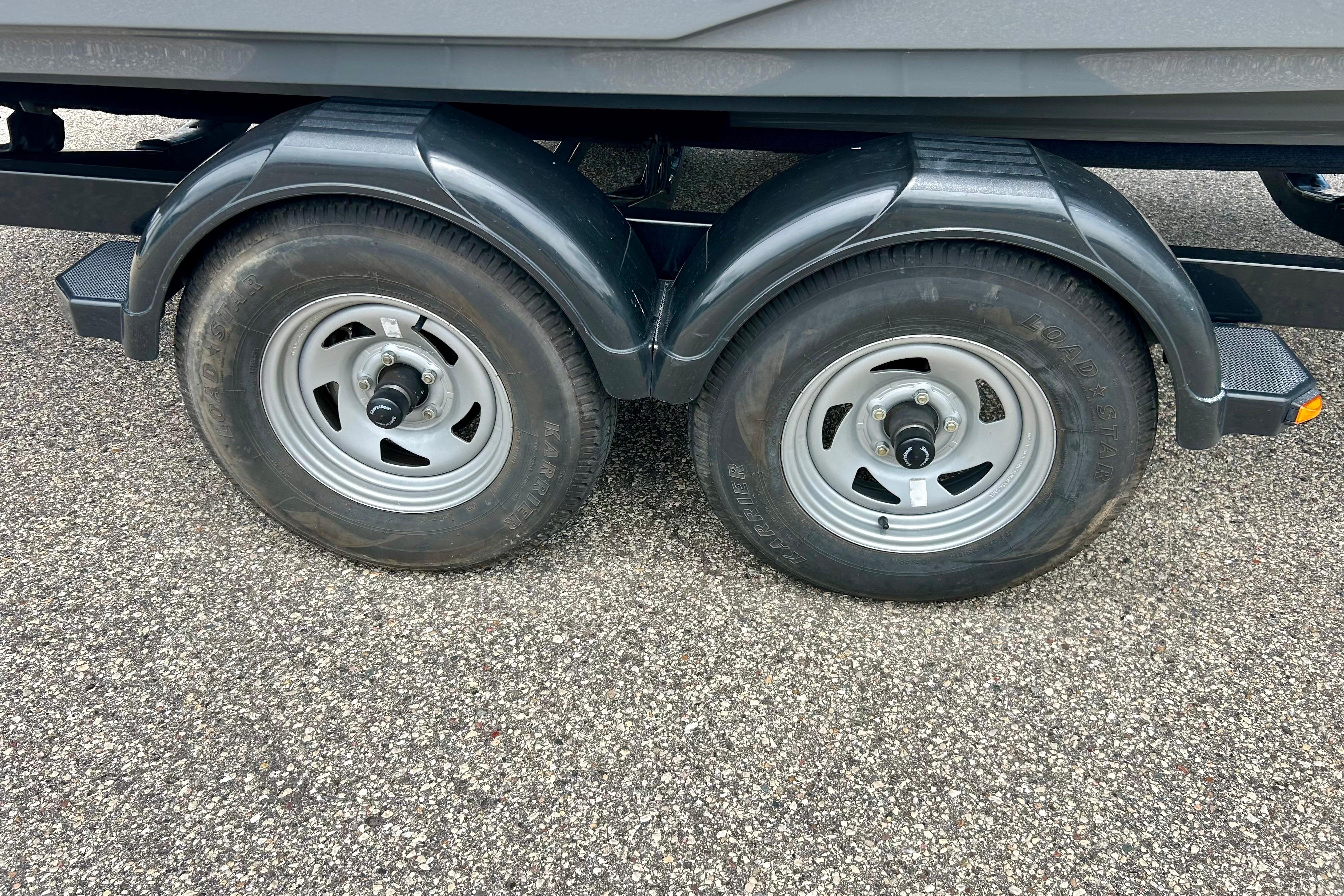 Trailer wheels of a 2015 Yamaha Boats AR210 on asphalt surface.