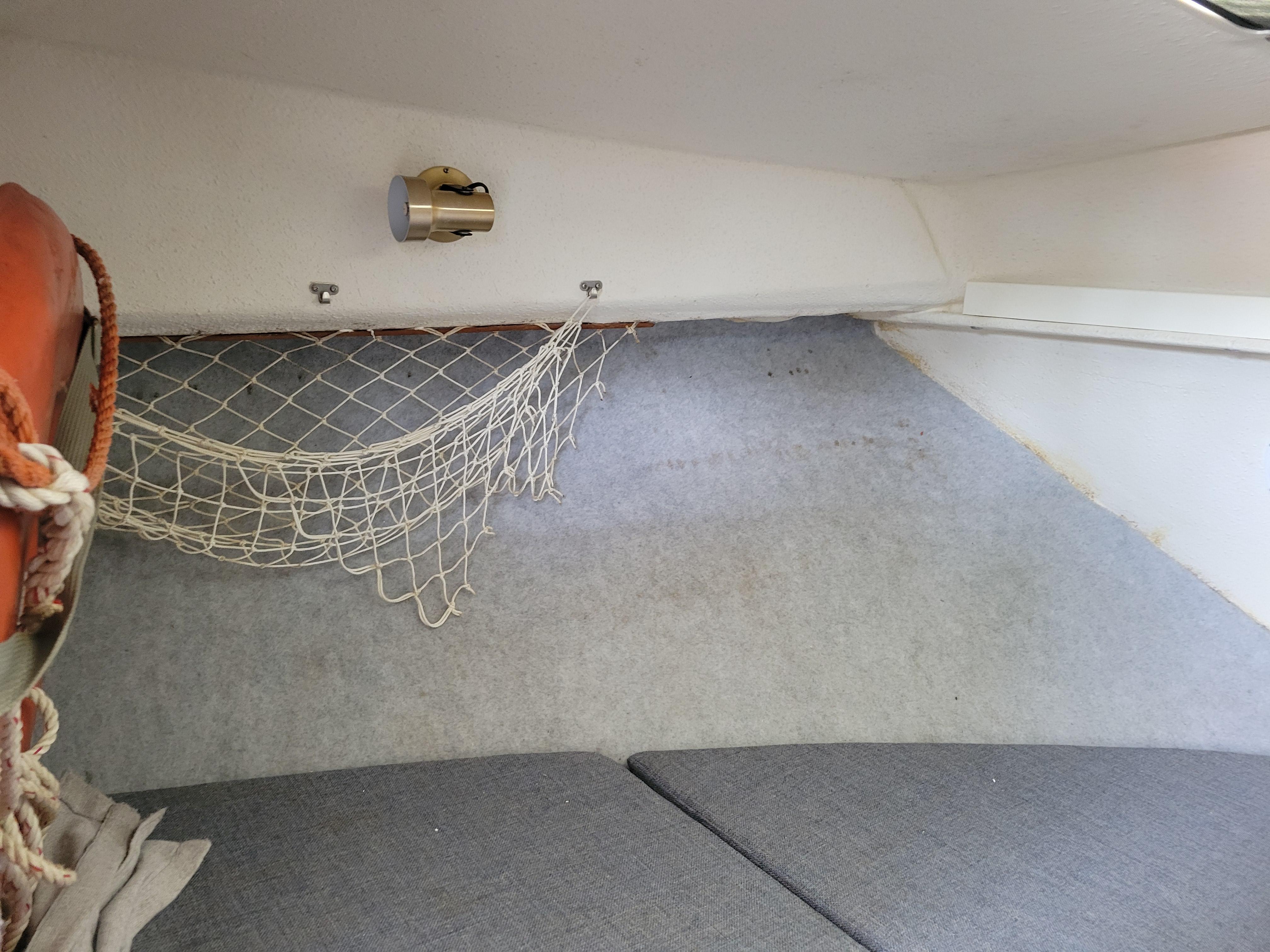Interior of 1999 SeaSport 2400 XL Limited boat with netting and light fixture.