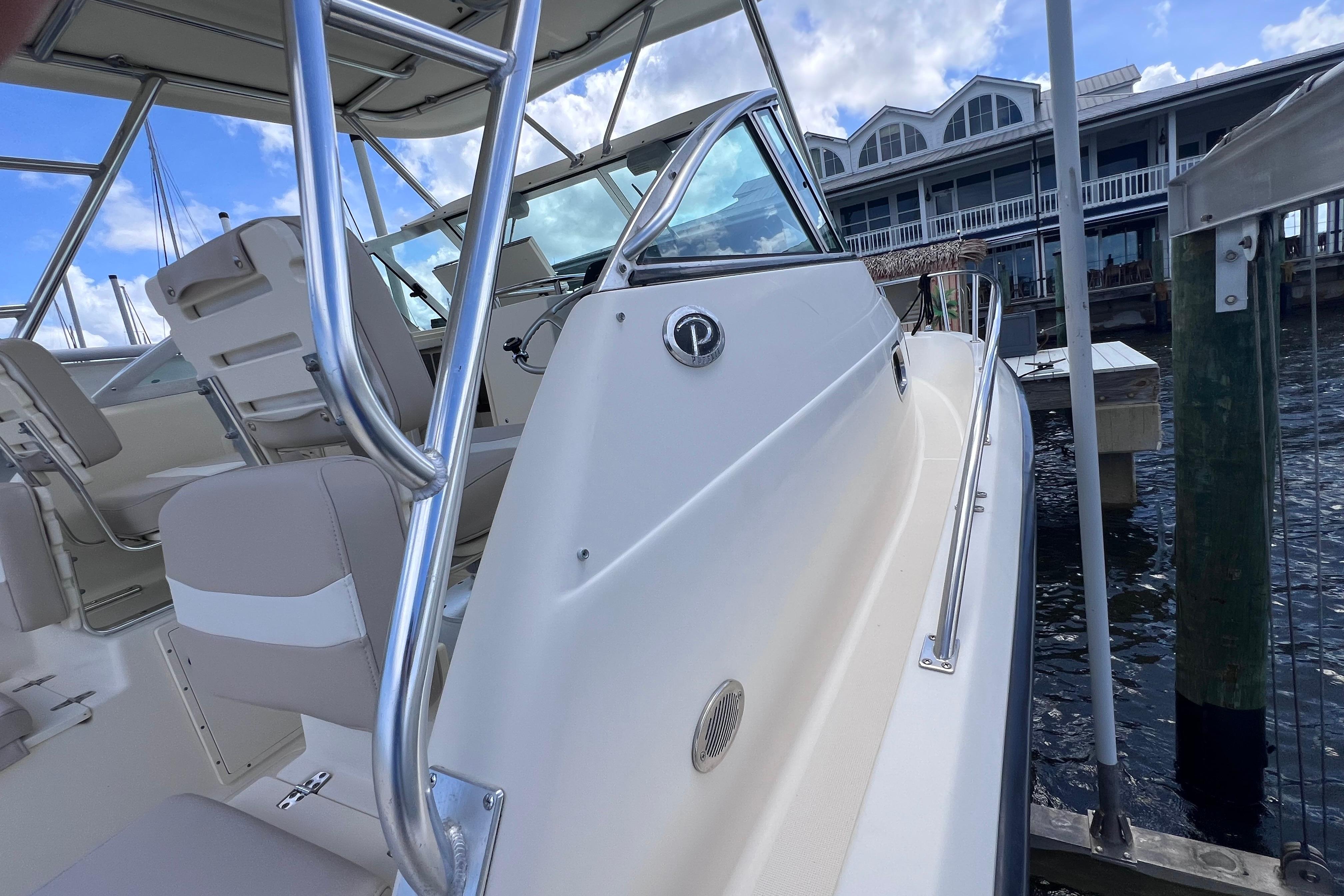 2004 Pursuit 2870 Walkaround boat docked near waterfront building under blue sky.