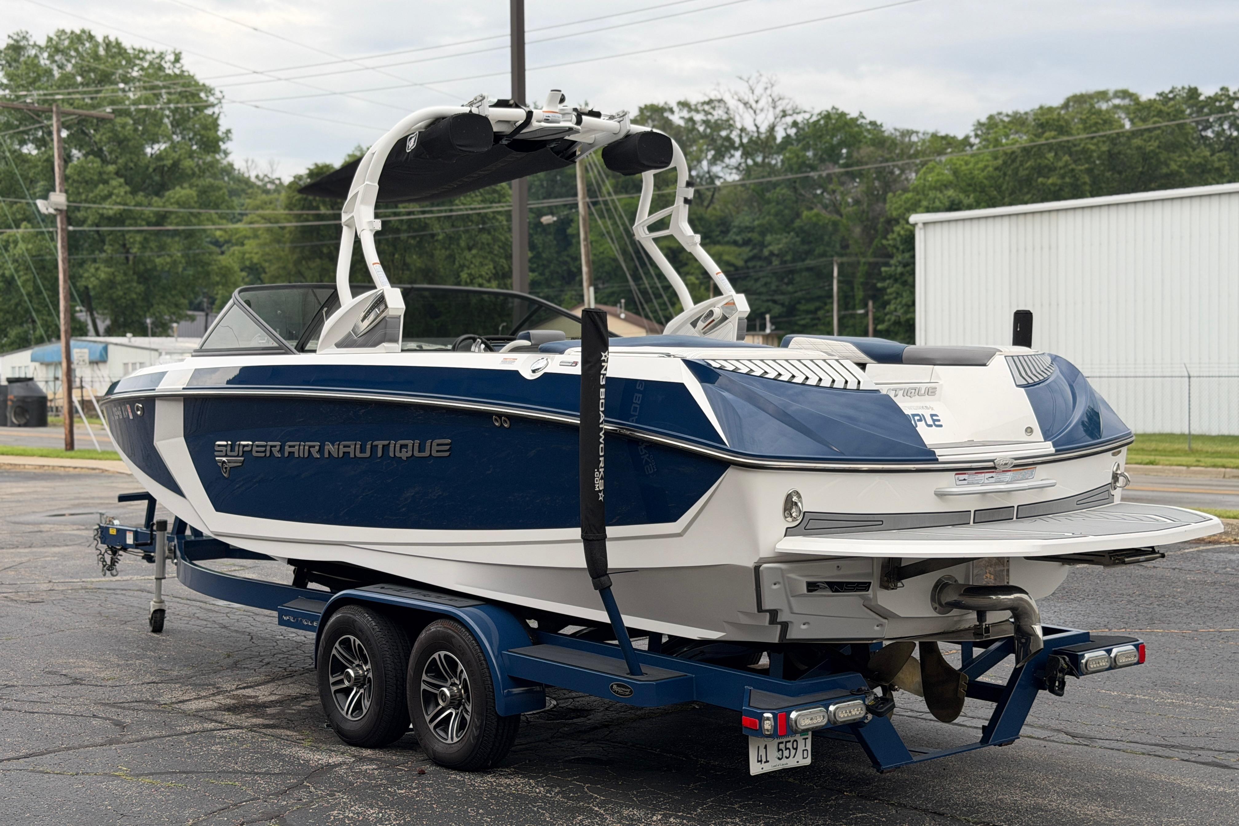 2016 Naitique G25 boat on trailer, blue and white design, parked outdoors.