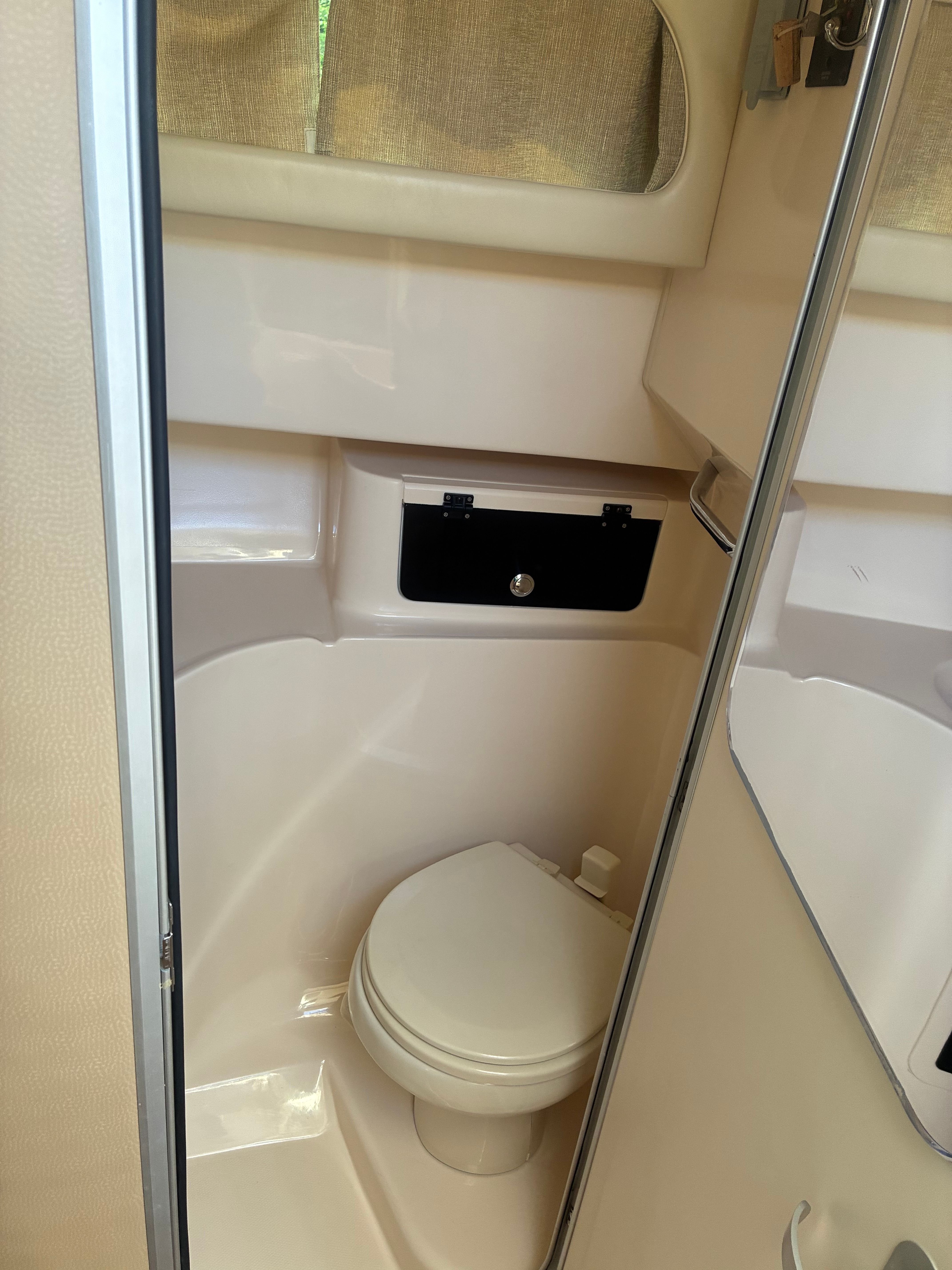 Interior view of a boat toilet with beige interior and a small window.
