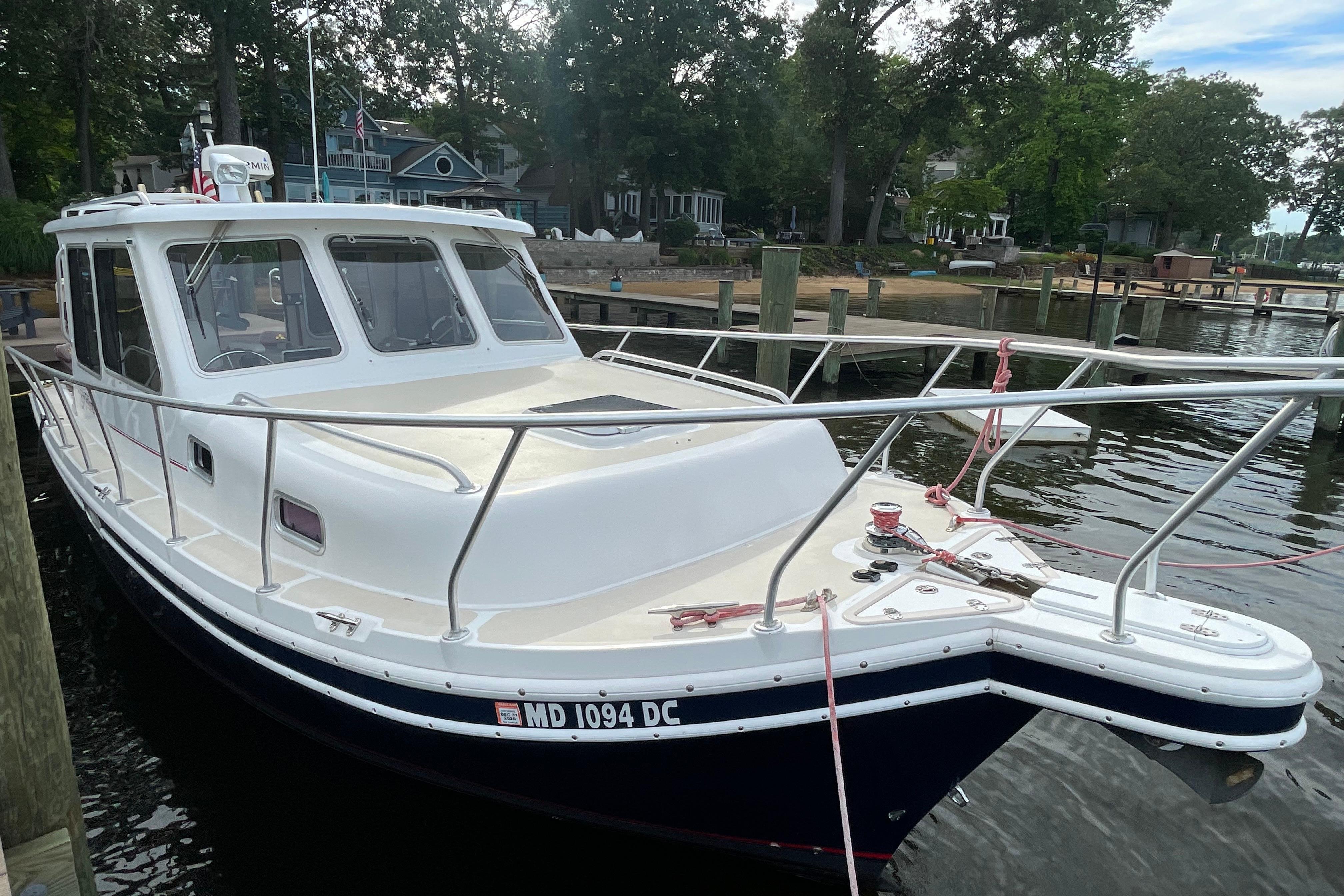 2005 Fox Island Thirty Sedan Cruiser docked by a scenic waterfront.