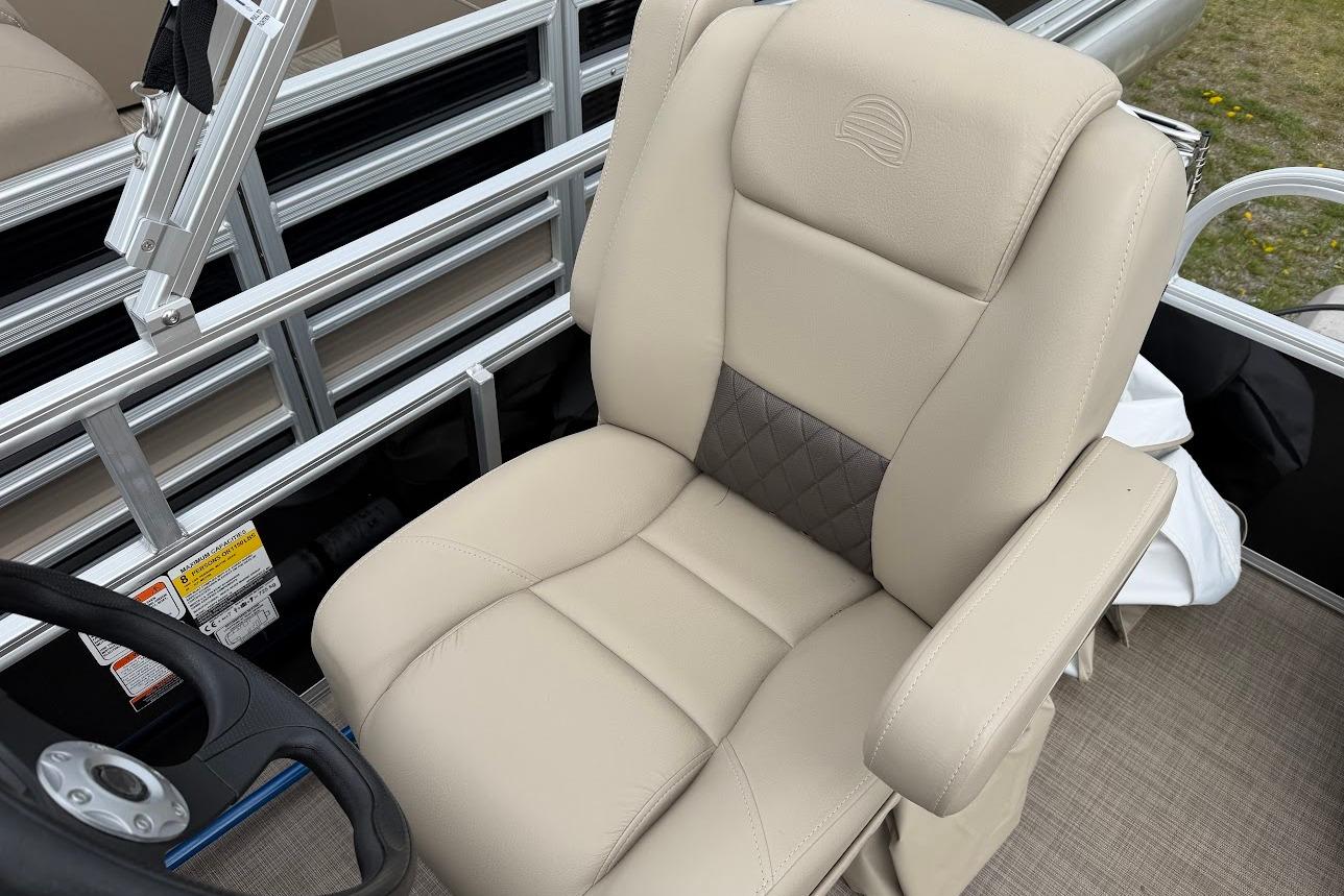 2025 Sun Tracker Party Barge 16 DLX captain's chair with beige upholstery and armrests.