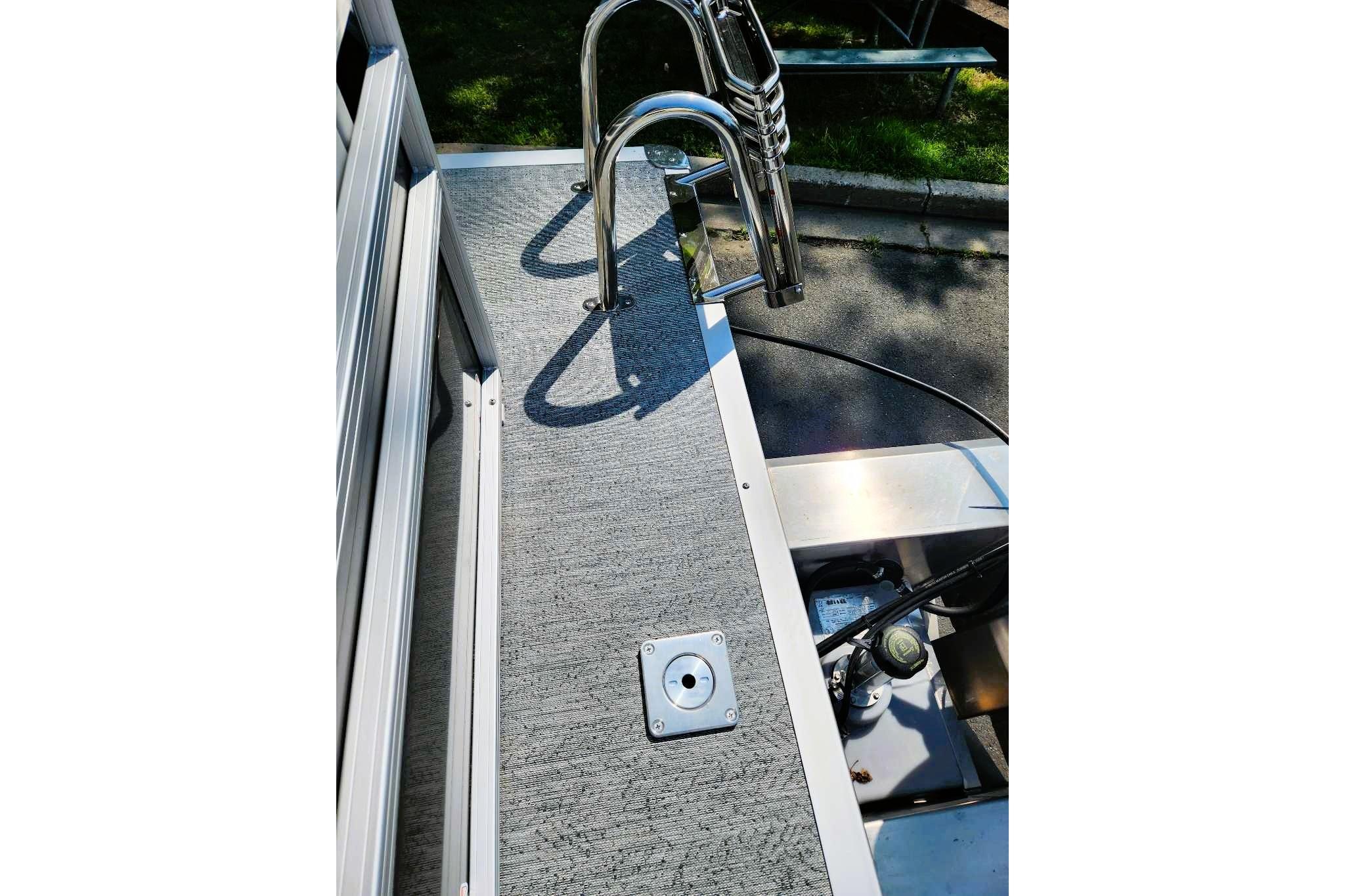2026 Sun Tracker Fishin' Barge 20 DLX deck with metal railing and textured flooring.