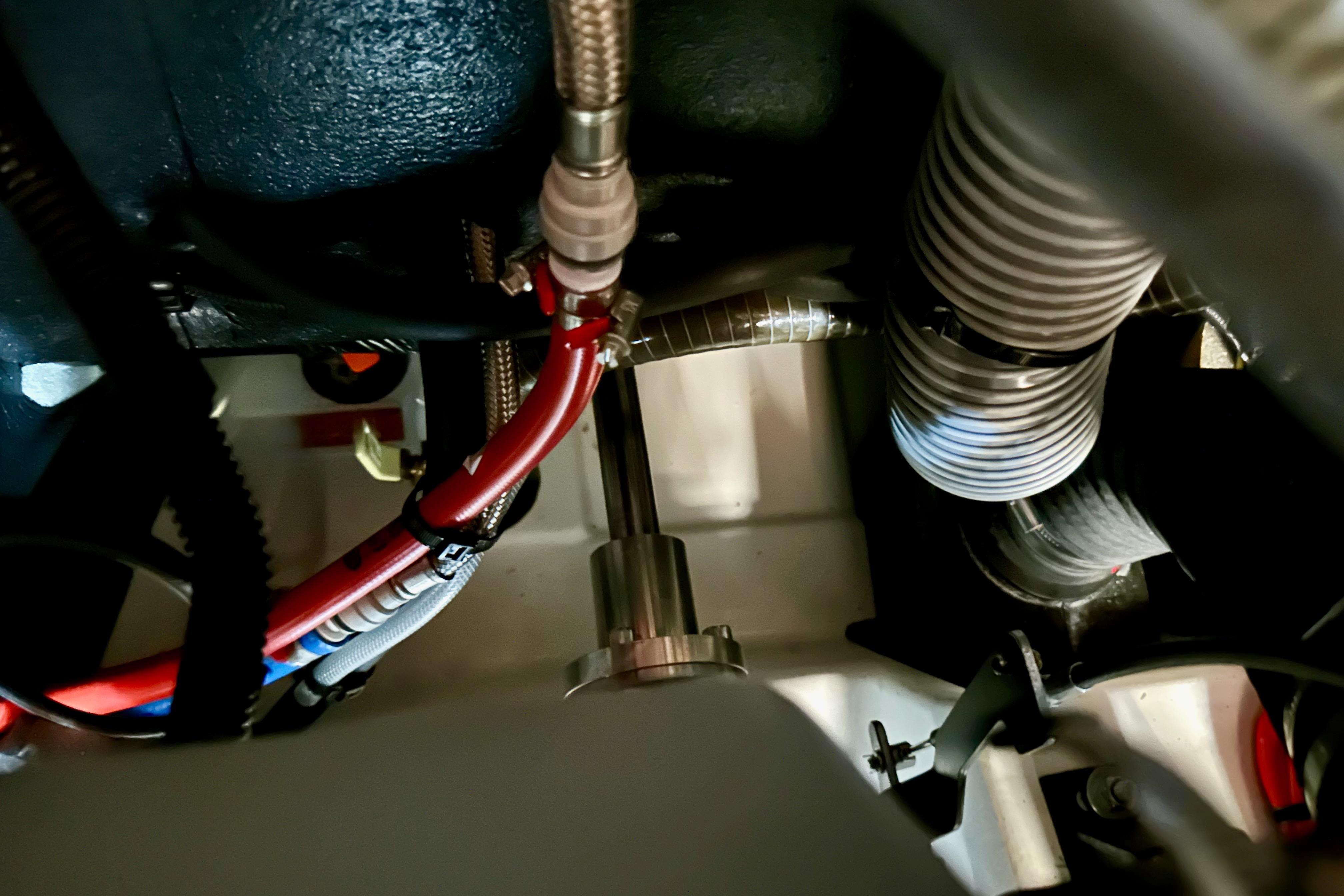 Engine compartment of 2024 Jeanneau Sun Odyssey 410 sailboat, showing hoses and wiring.