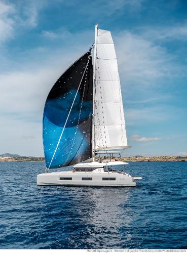 2025 Lagoon 55 catamaran sailing on open sea under clear blue sky.