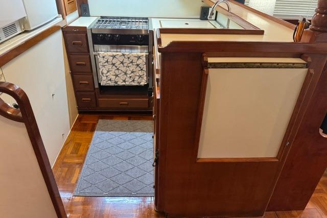 1986 Kadey-Krogen 42 yacht kitchen with stove, wooden cabinetry, and parquet flooring.