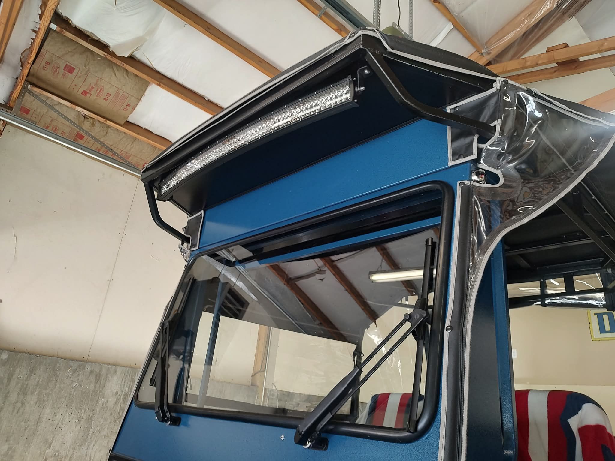 The image shows the T-top of a Custom Weld 23' sled boat in a garage.