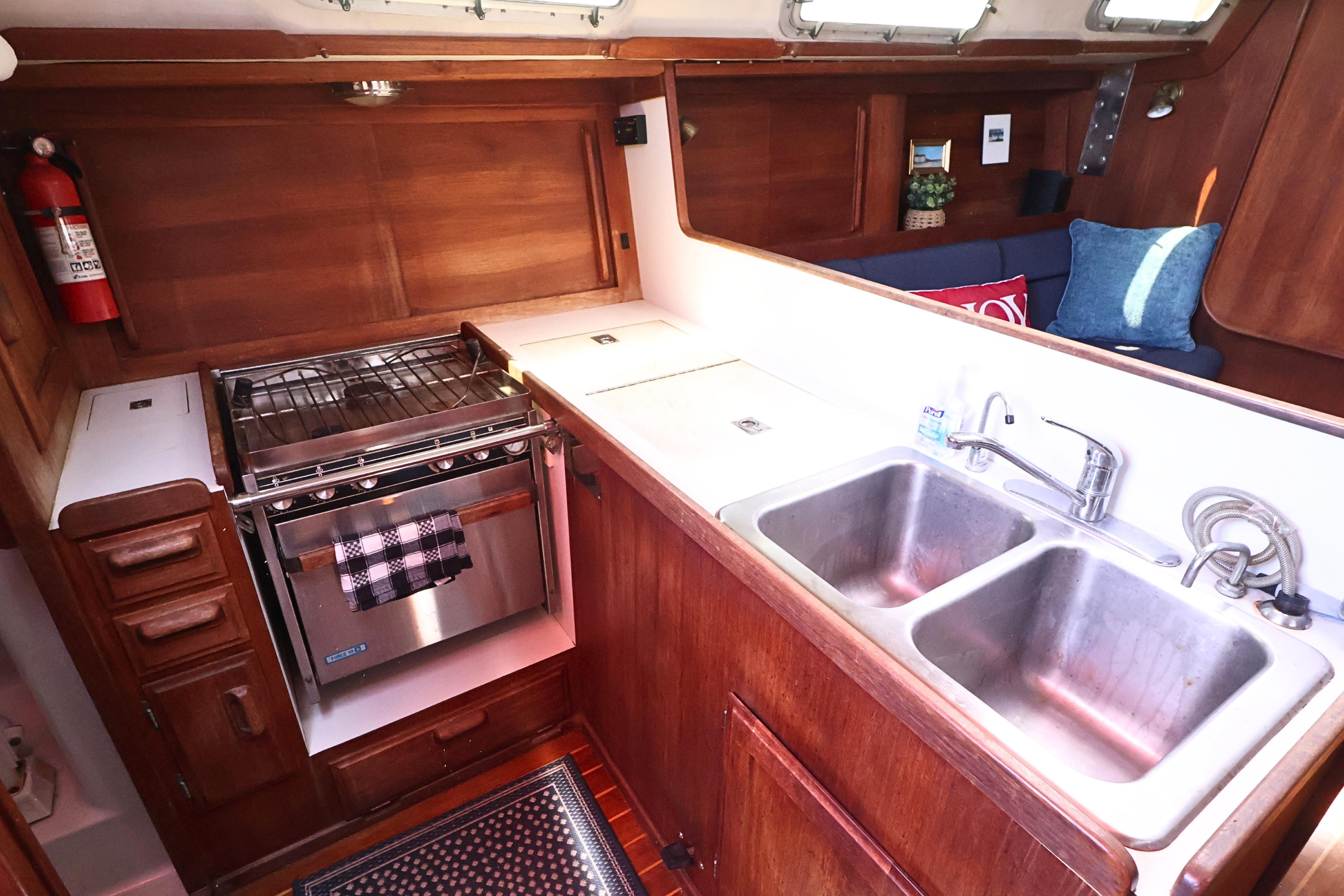 1989 J Boat J 40 interior kitchen with stove, double sink, and wooden cabinetry.