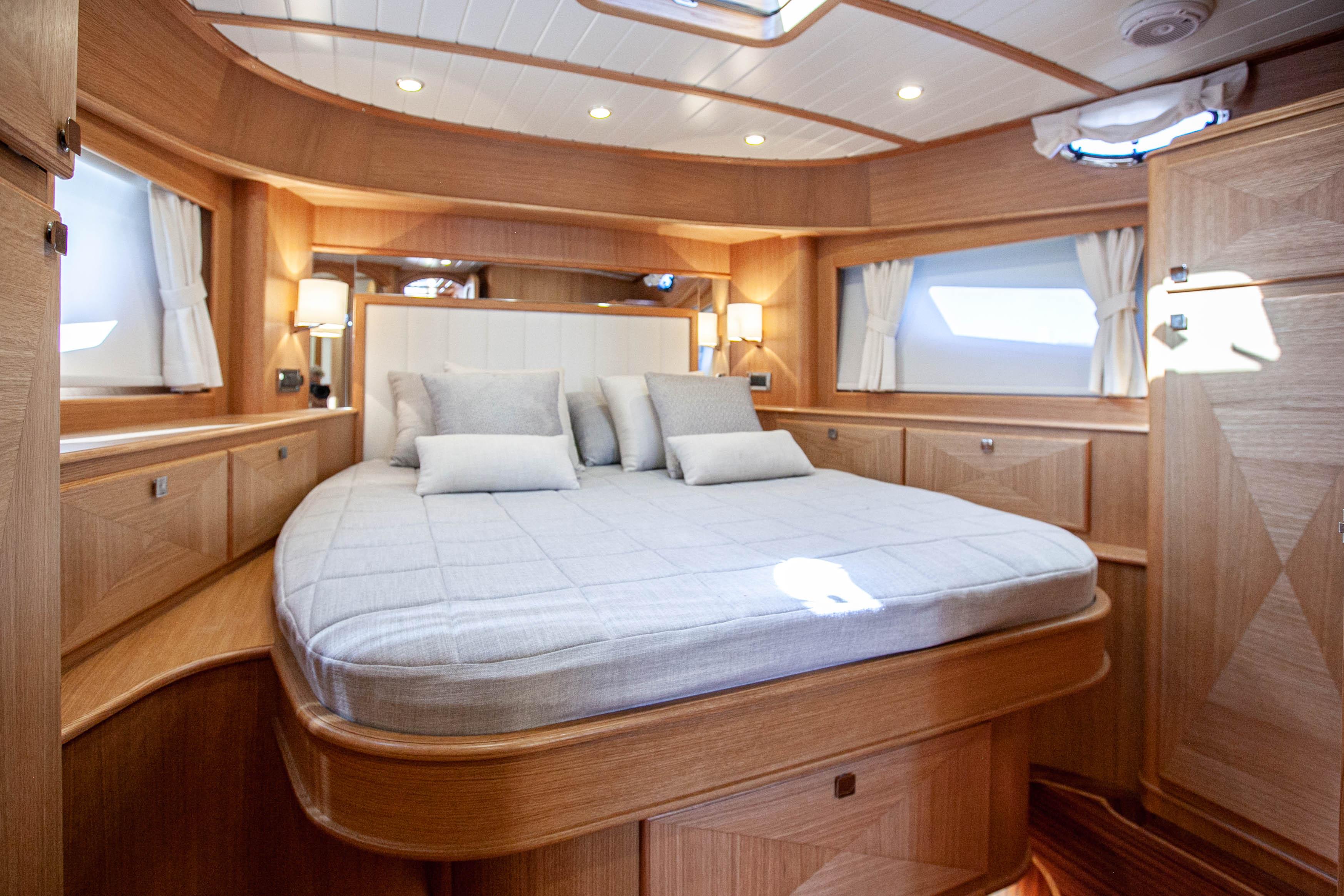 Luxurious cabin interior of 2023 Vicem 55 yacht with elegant wood finish and cozy bedding.