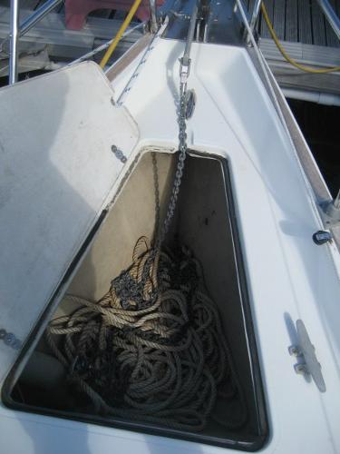 An open anchor locker with ropes and chain on a boat.