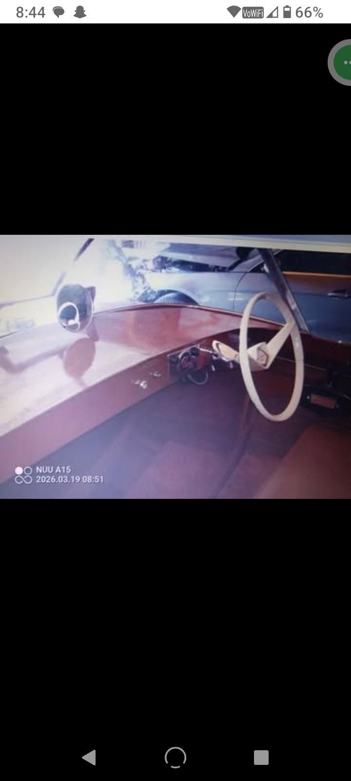 Interior of a 1957 Chris-Craft Comet boat with white steering wheel.