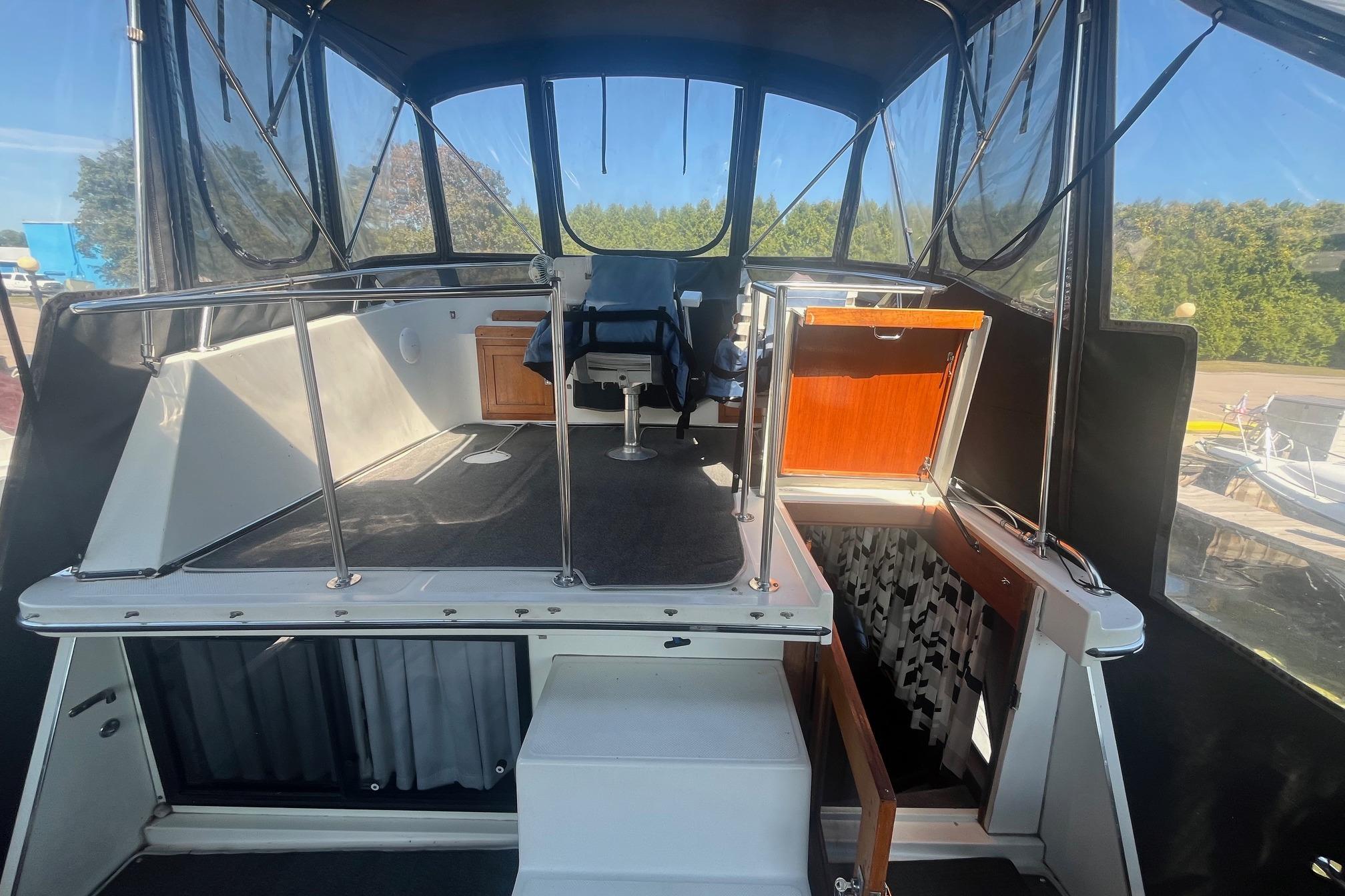 1990 Cooper Prowler 35 boat interior with seating and storage, featuring clear windows and railing.