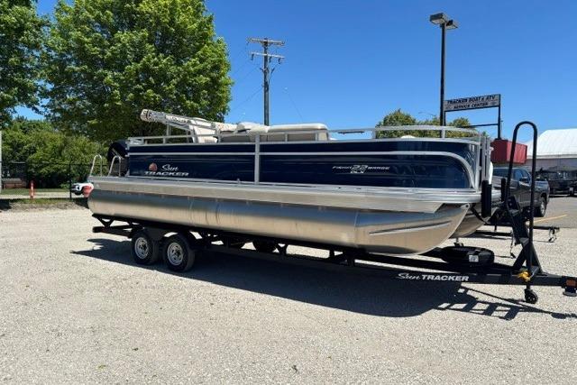2025 Sun Tracker Fishin' Barge 22 DLX pontoon boat on trailer in sunny outdoor setting.