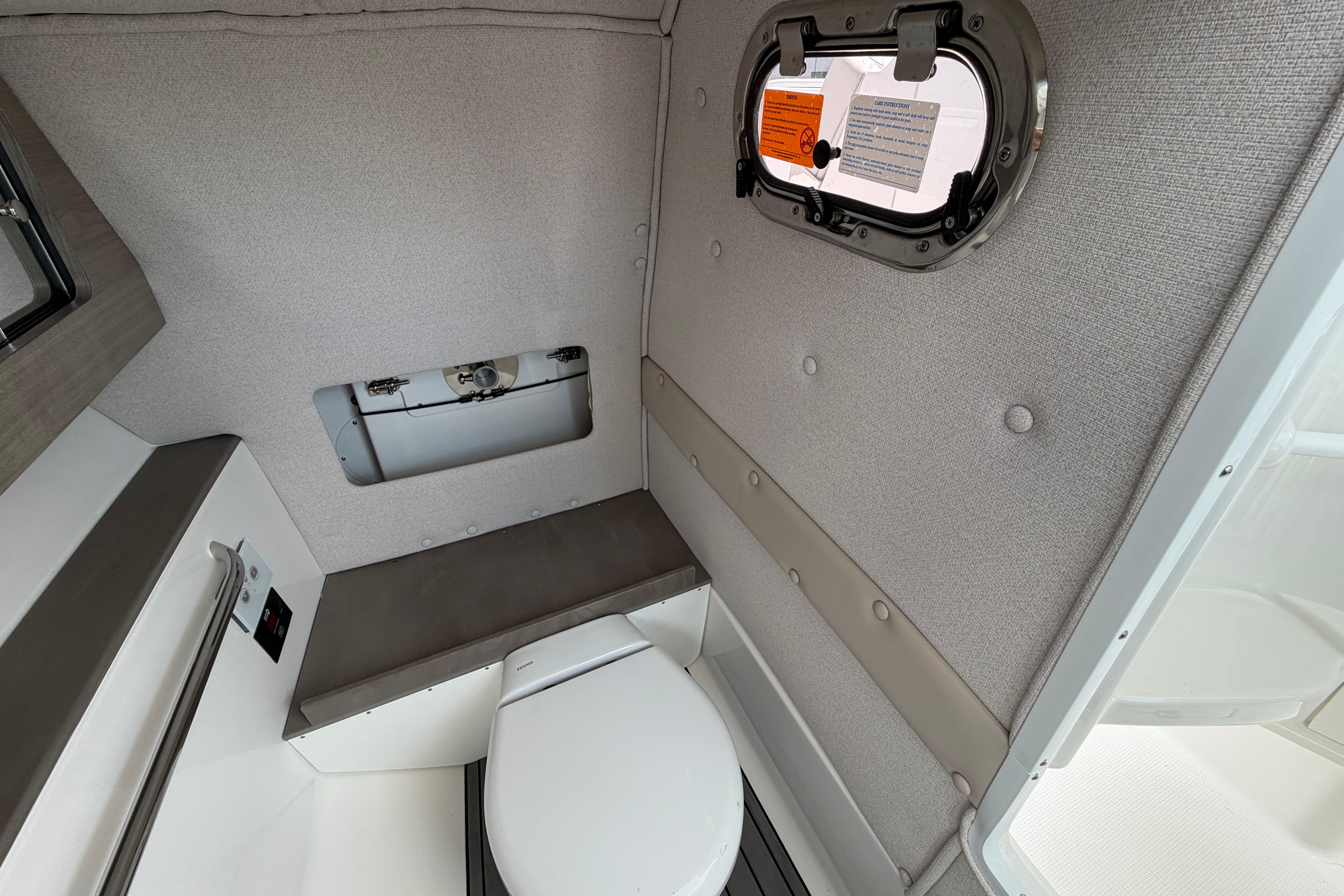 Interior of 2026 Edgewater 248CX Crossover boat featuring a compact marine toilet.