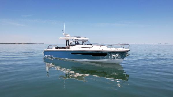 2025 Nimbus T11 boat on calm water under clear blue sky.