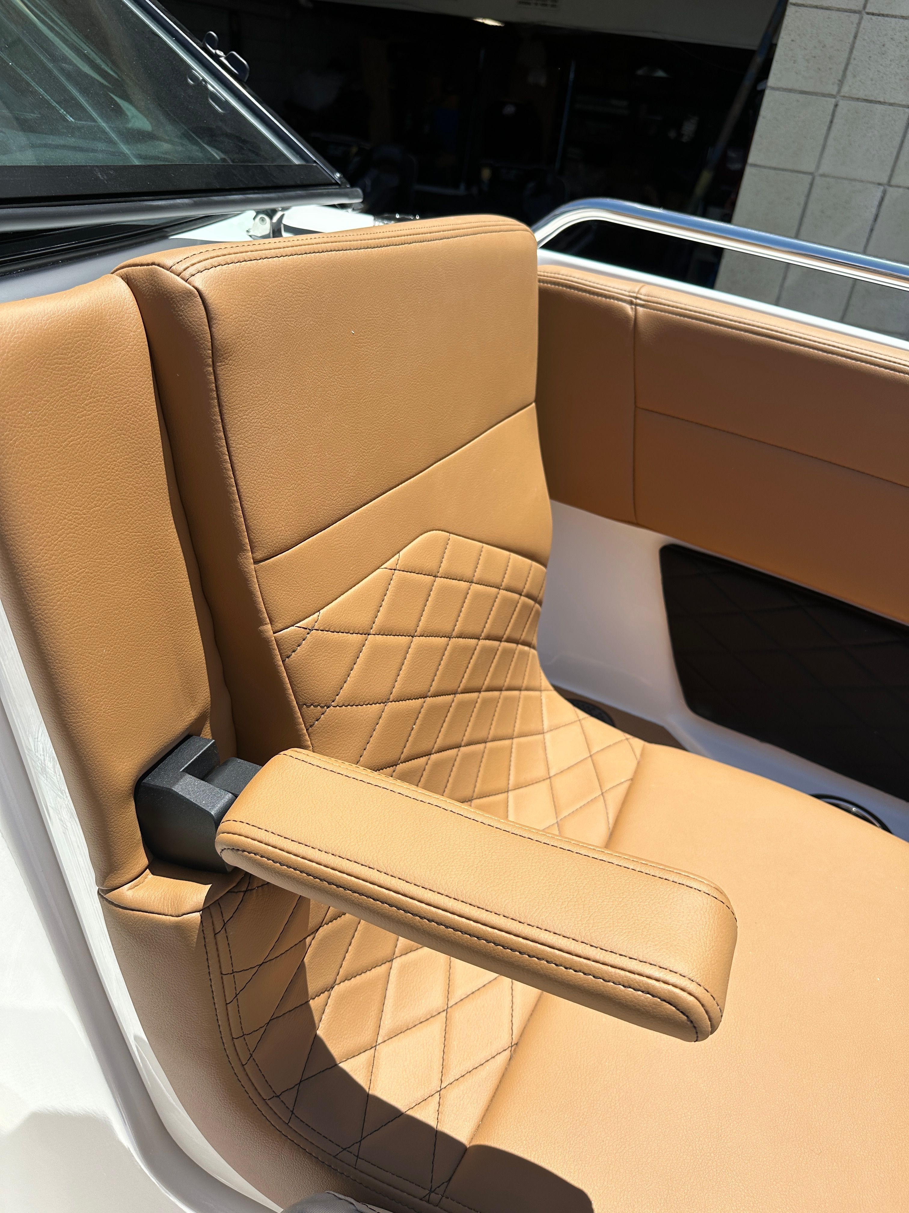 Close-up of a luxurious upholstered boat seat with armrest and quilted pattern.