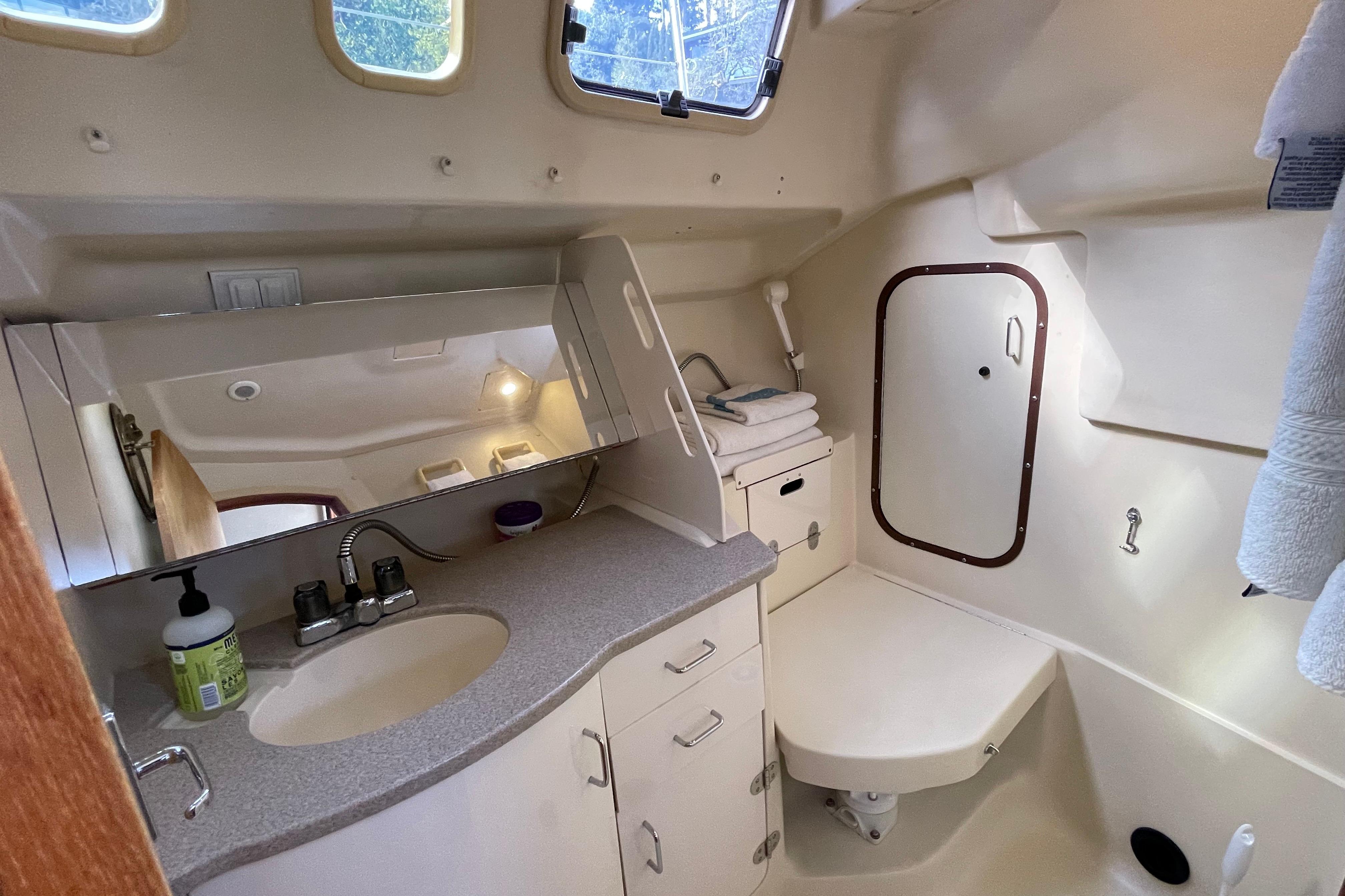 Interior of 2000 Hunter 340 yacht bathroom with sink, mirror, and storage cabinets.