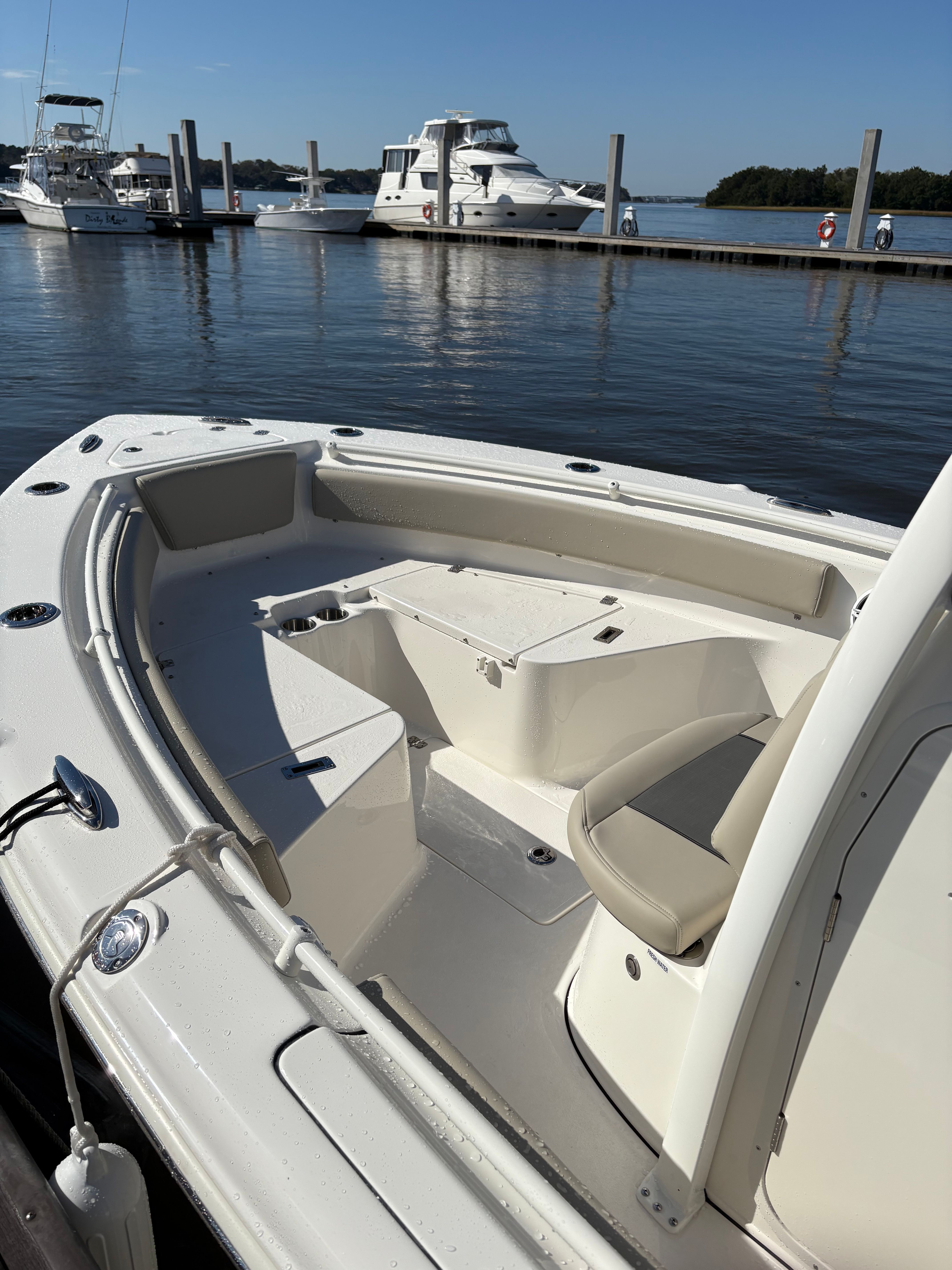 A Key West 239 FSR boat docked. It features an open deck and is on calm water.