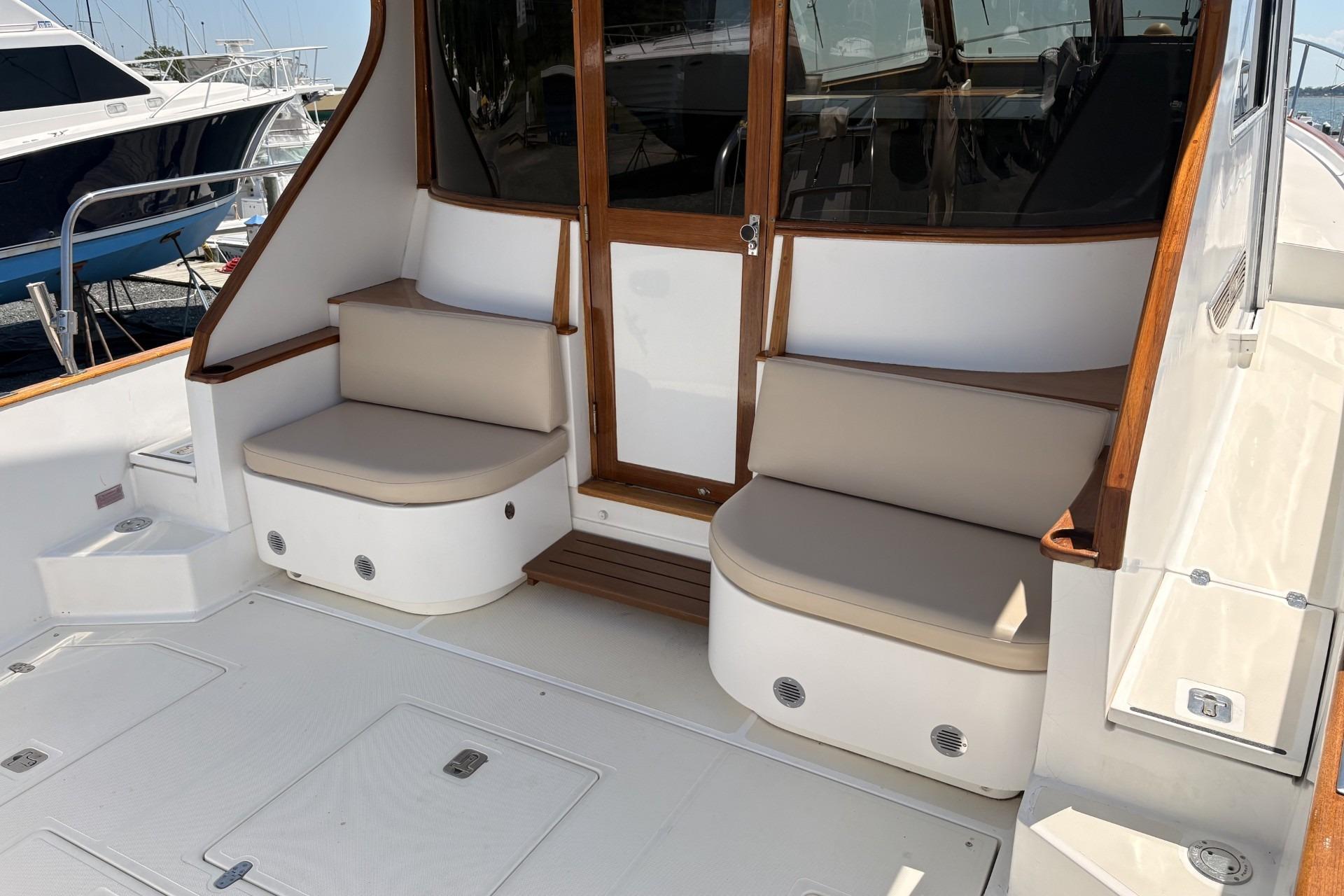 Luxurious boat seating area with beige cushions and wooden accents, docked at a marina.