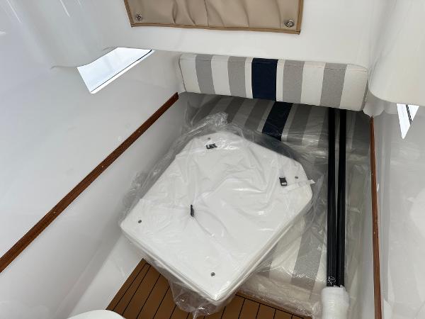 Interior of 2025 Southport 33 FE boat with striped cushions and wooden flooring.