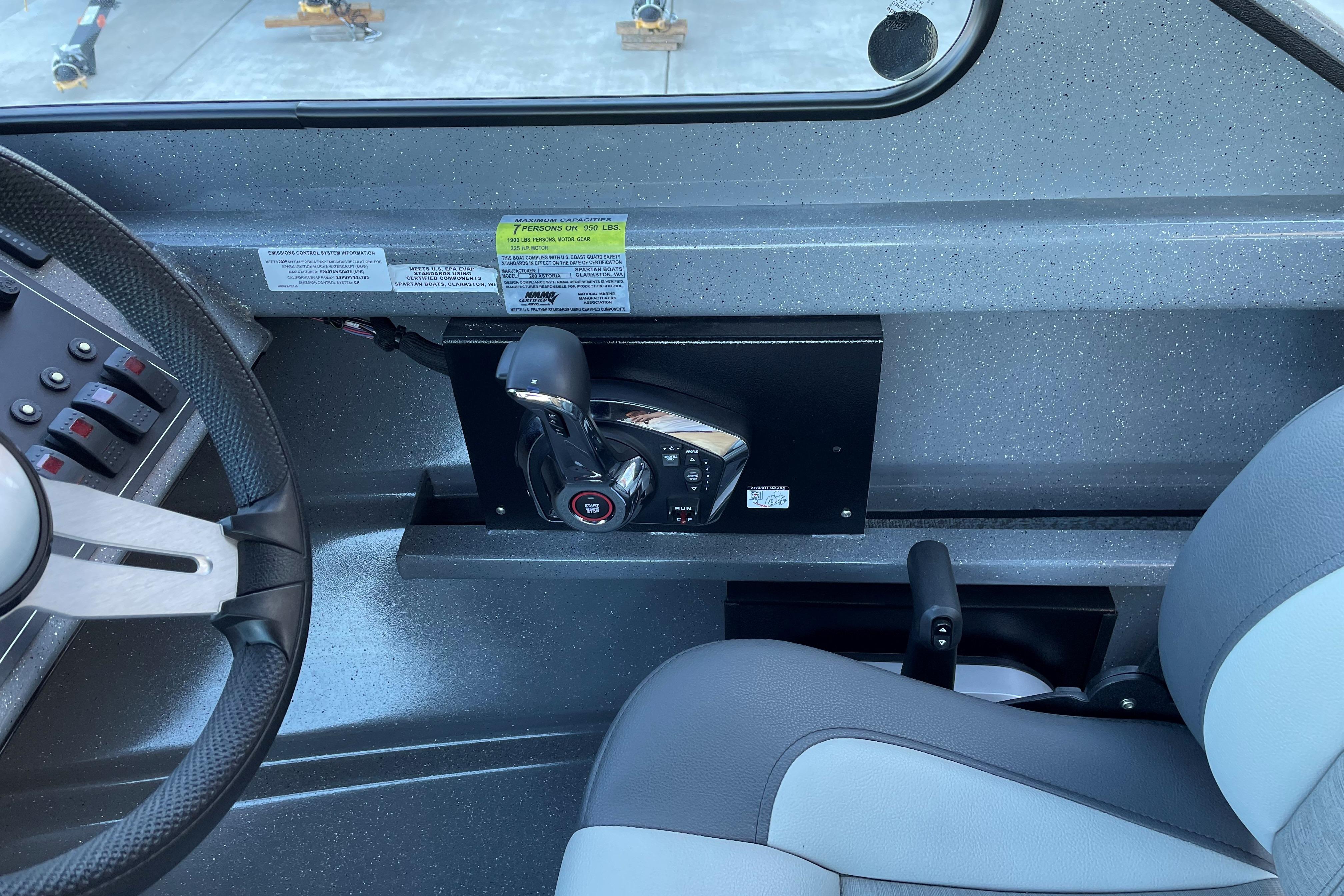 Interior of 2025 Spartan 200 Astoria boat, featuring steering wheel and control panel.
