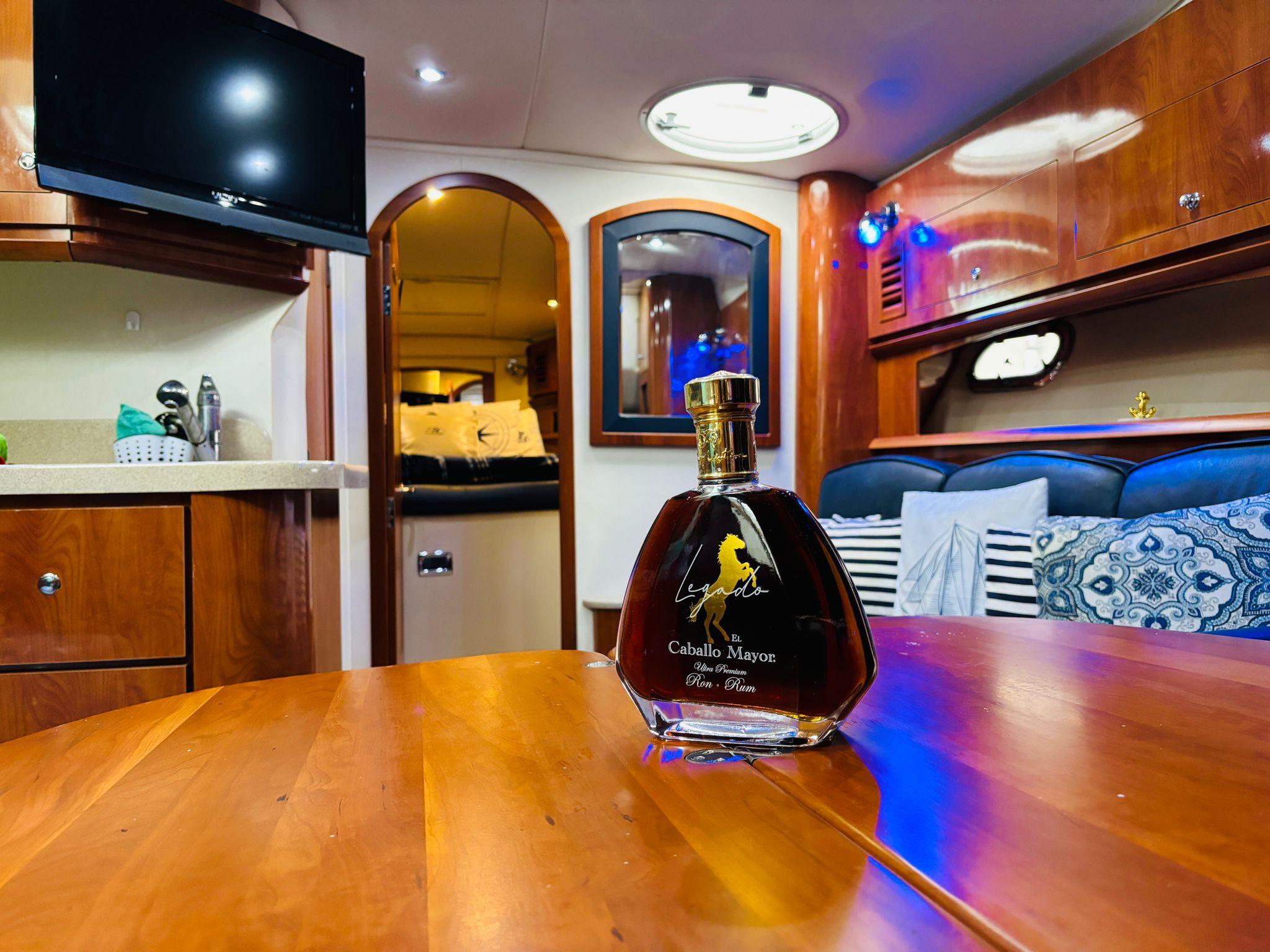 Luxurious 2005 Four Winns 378 Vista yacht interior with elegant wooden table and premium liquor bottle.