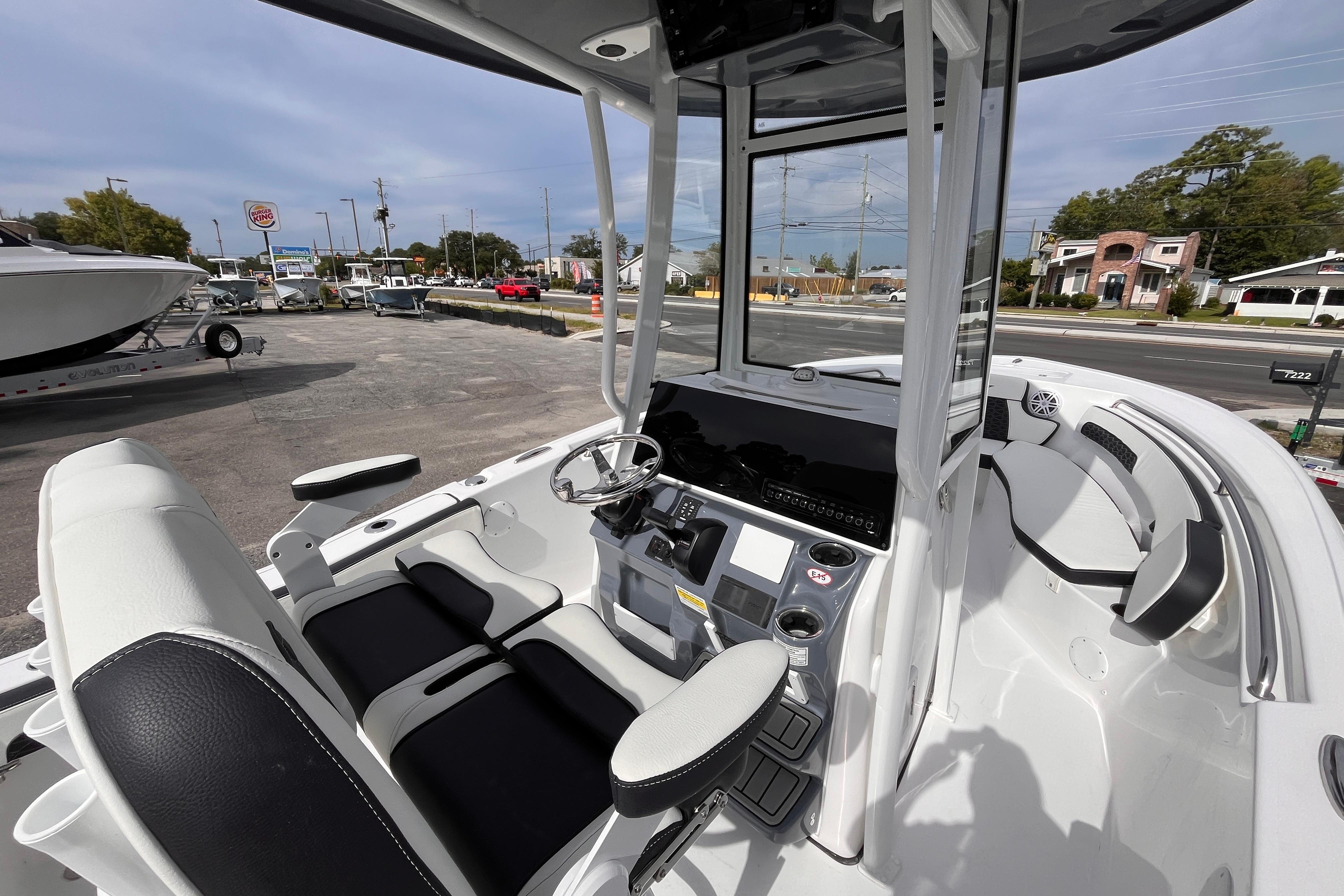 2026 Tidewater 220 LXF boat interior with modern helm and seating, parked outdoors.