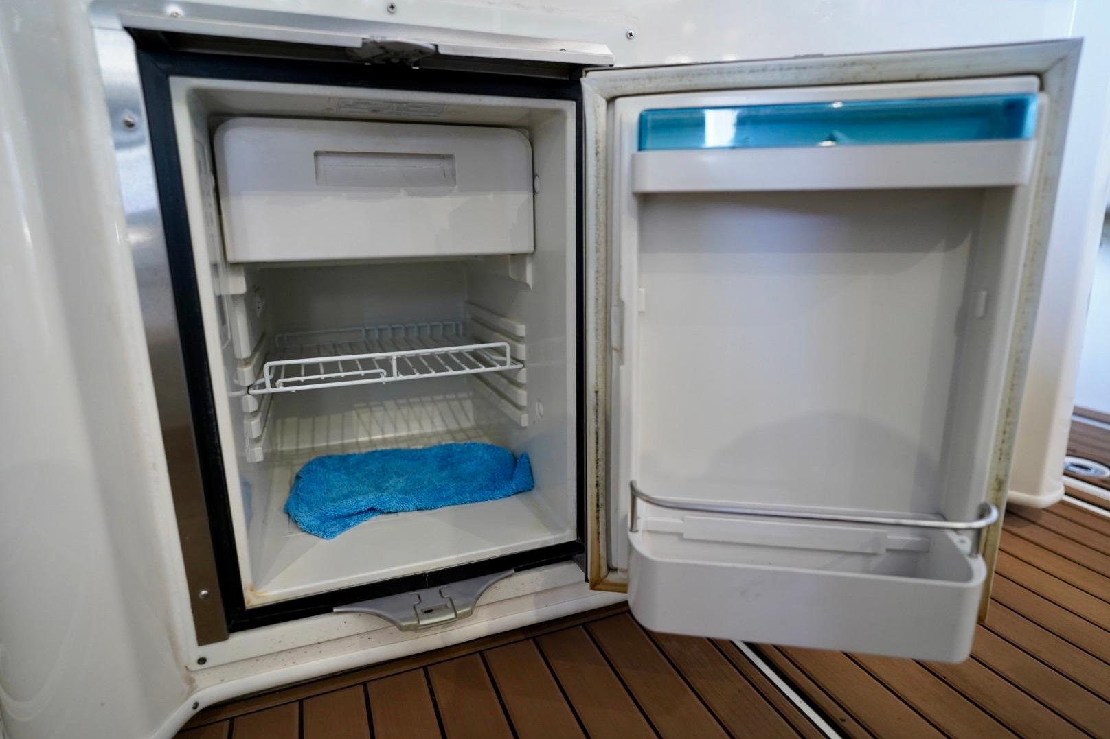 Open refrigerator on 2019 Cobia 344 Center Console boat, showing interior shelves and blue cloth.