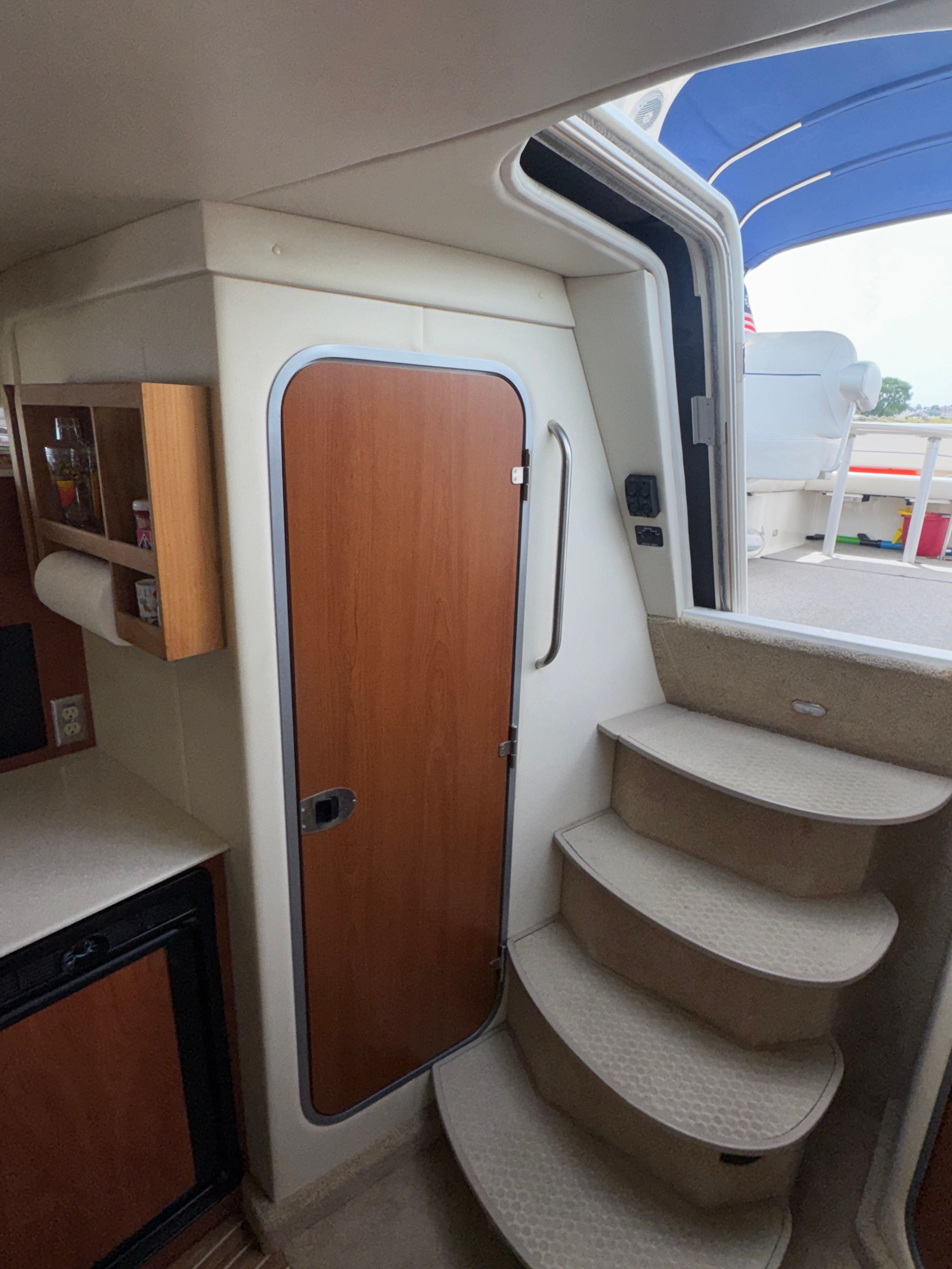 Interior of a 2008 Bayliner 340 with stairs and wooden door.