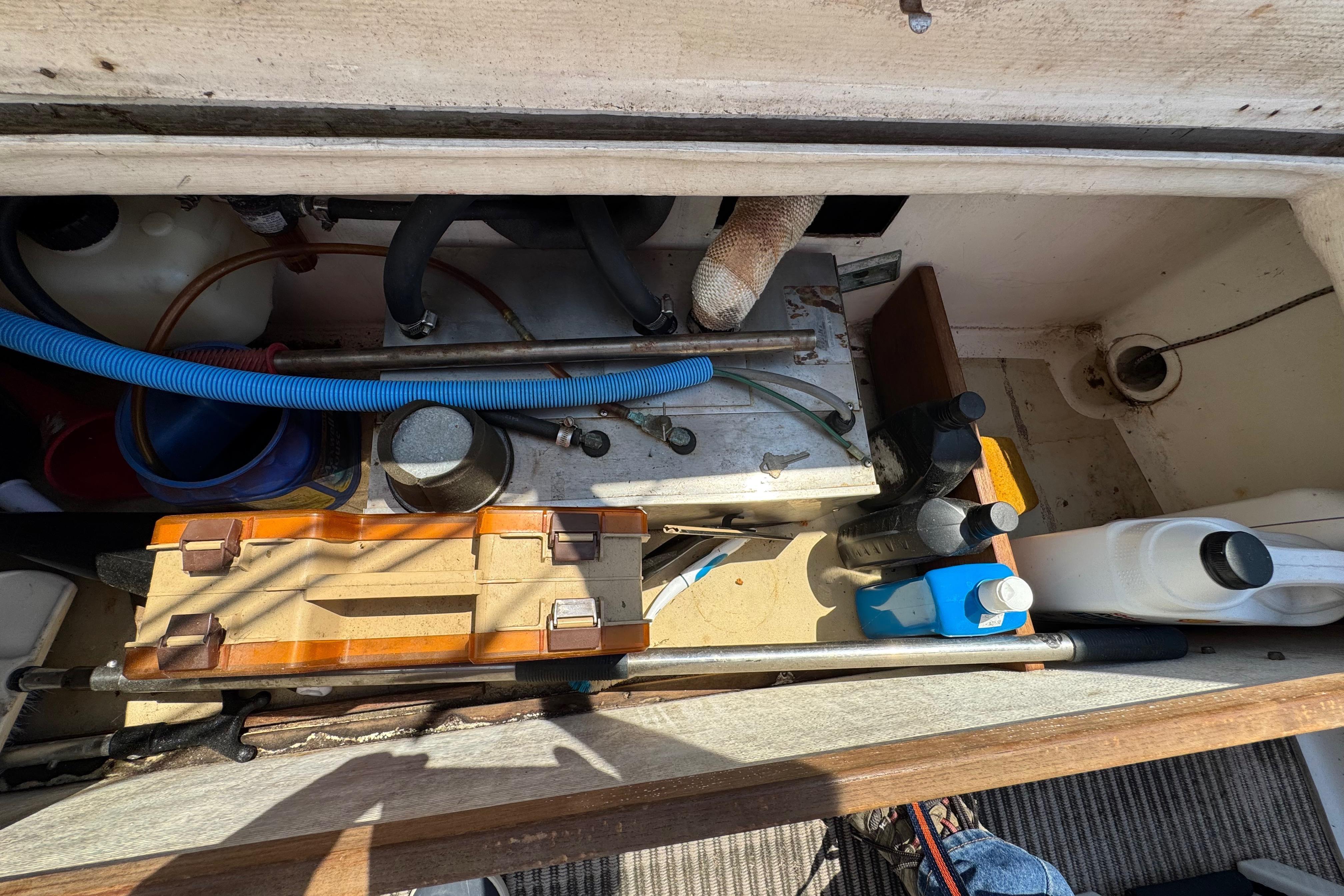 A view into the engine compartment of a 1989 Cape Dory 30 Motorsailer with various tools and equipment.