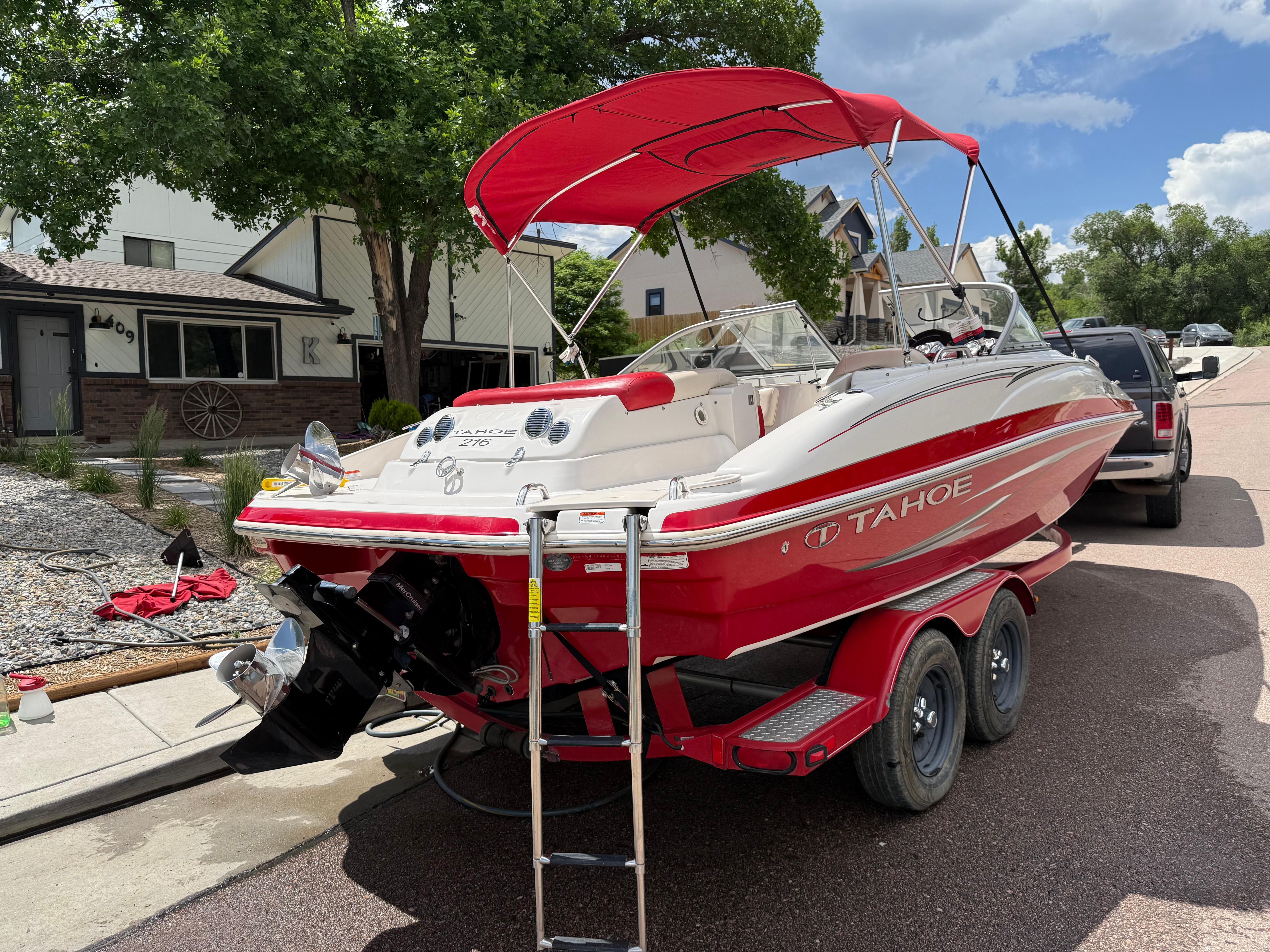 Red 2011 Tahoe 216 WT boat on trailer in residential area.