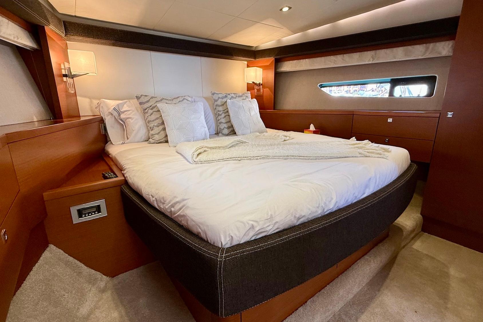Luxurious bedroom interior of 2012 Prestige 620S yacht with elegant bedding and wood finishes.