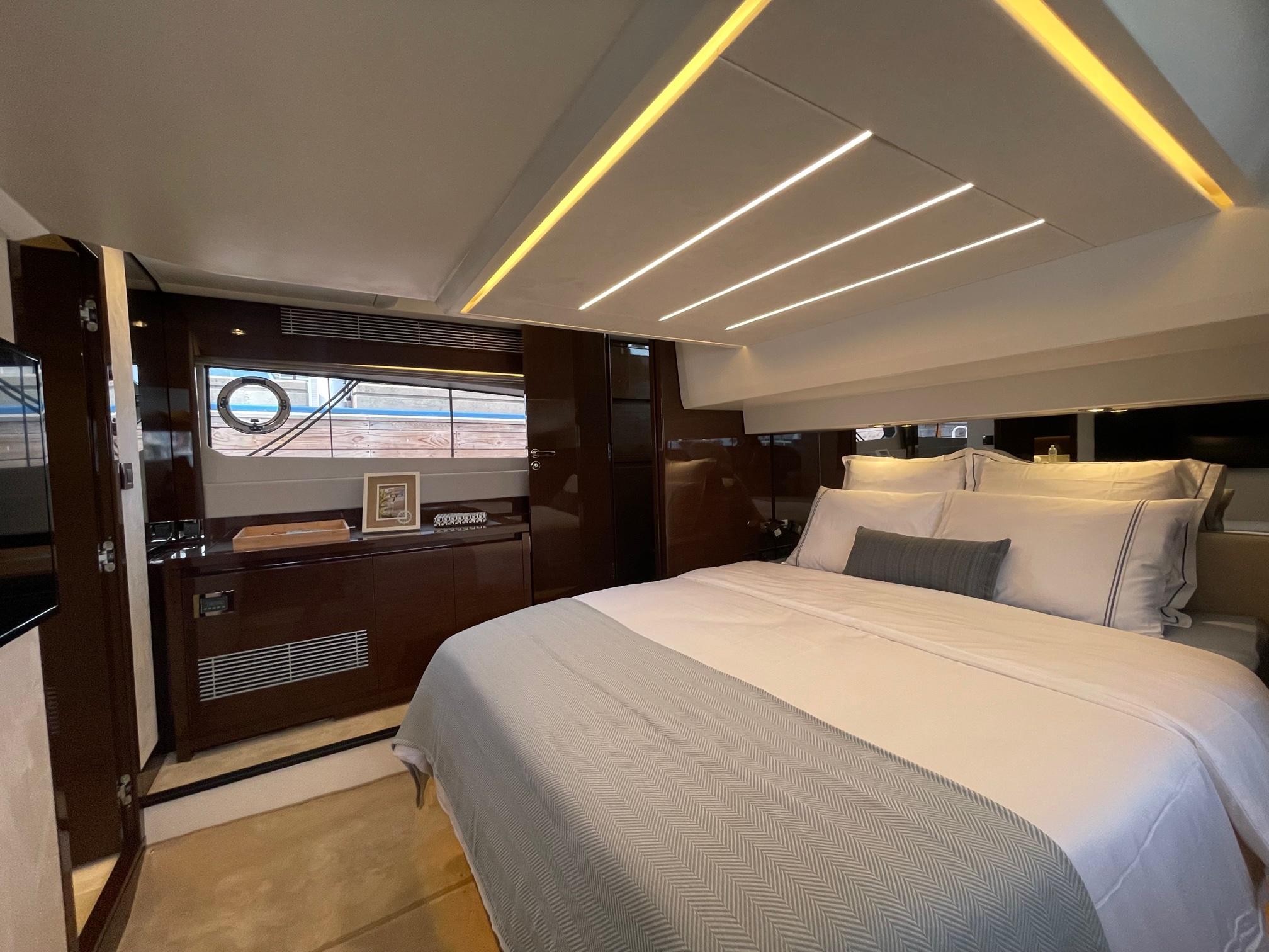Luxurious bedroom interior of 2024 Prestige 520 Flybridge yacht, featuring elegant design and ambient lighting.
