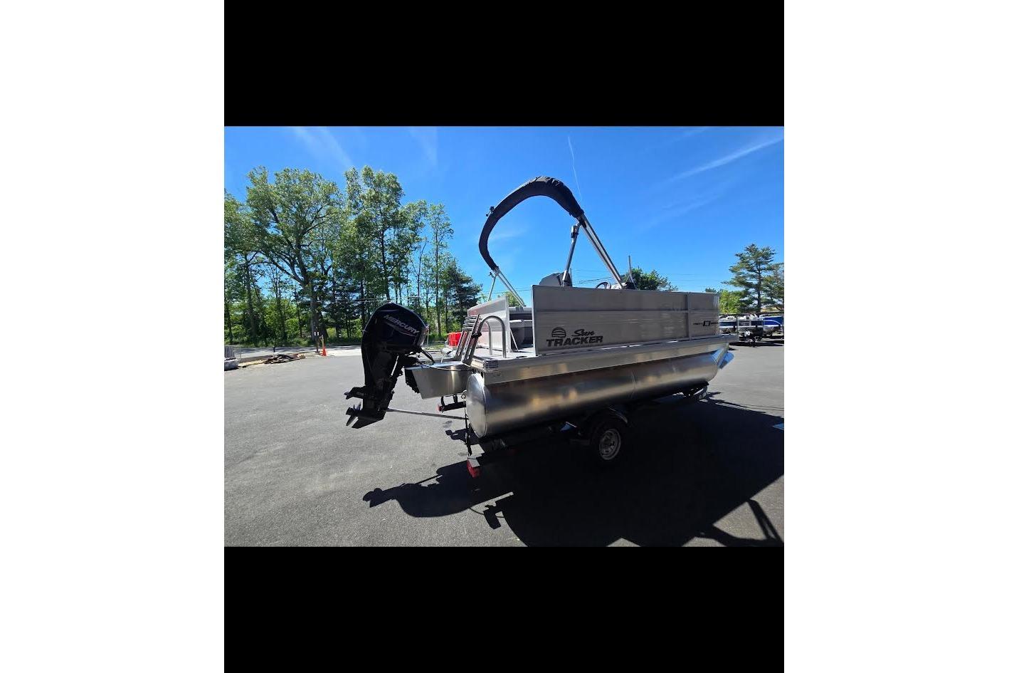 2026 Sun Tracker Party Barge 16 DLX pontoon boat on trailer, parked outdoors.