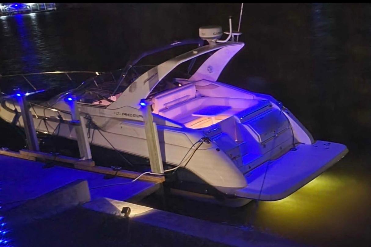 2003 Regal Commodore 3260 boat docked at night with blue and yellow lights.
