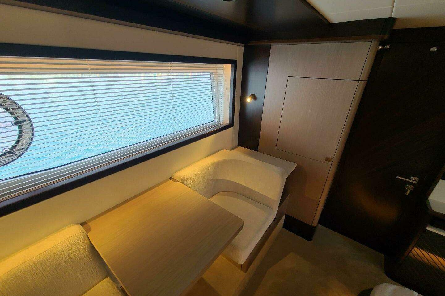 Luxurious interior of 2023 Sunseeker Manhattan 68 yacht with elegant seating and window view.