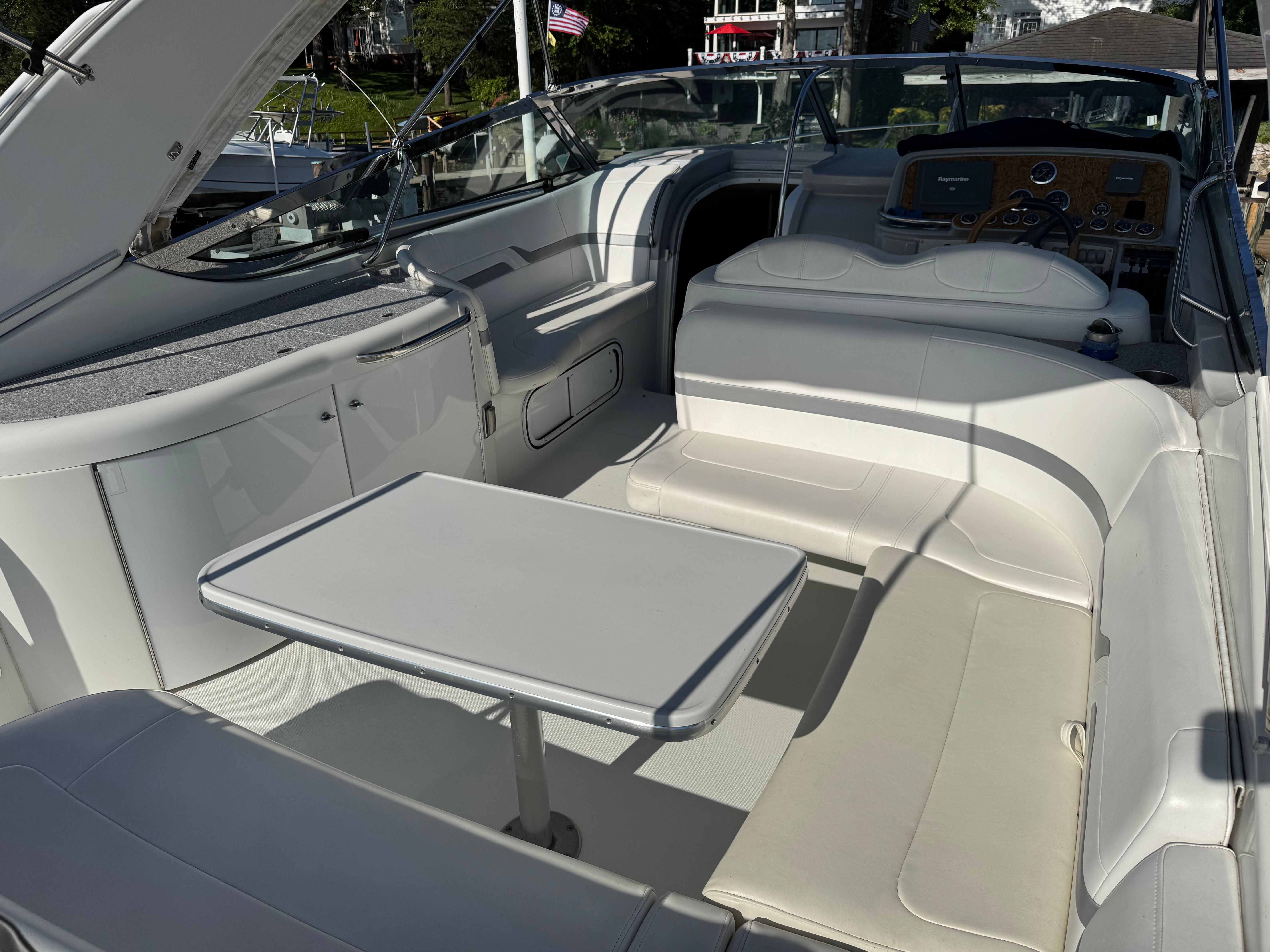 Interior of a luxury yacht with white seating and a table.
