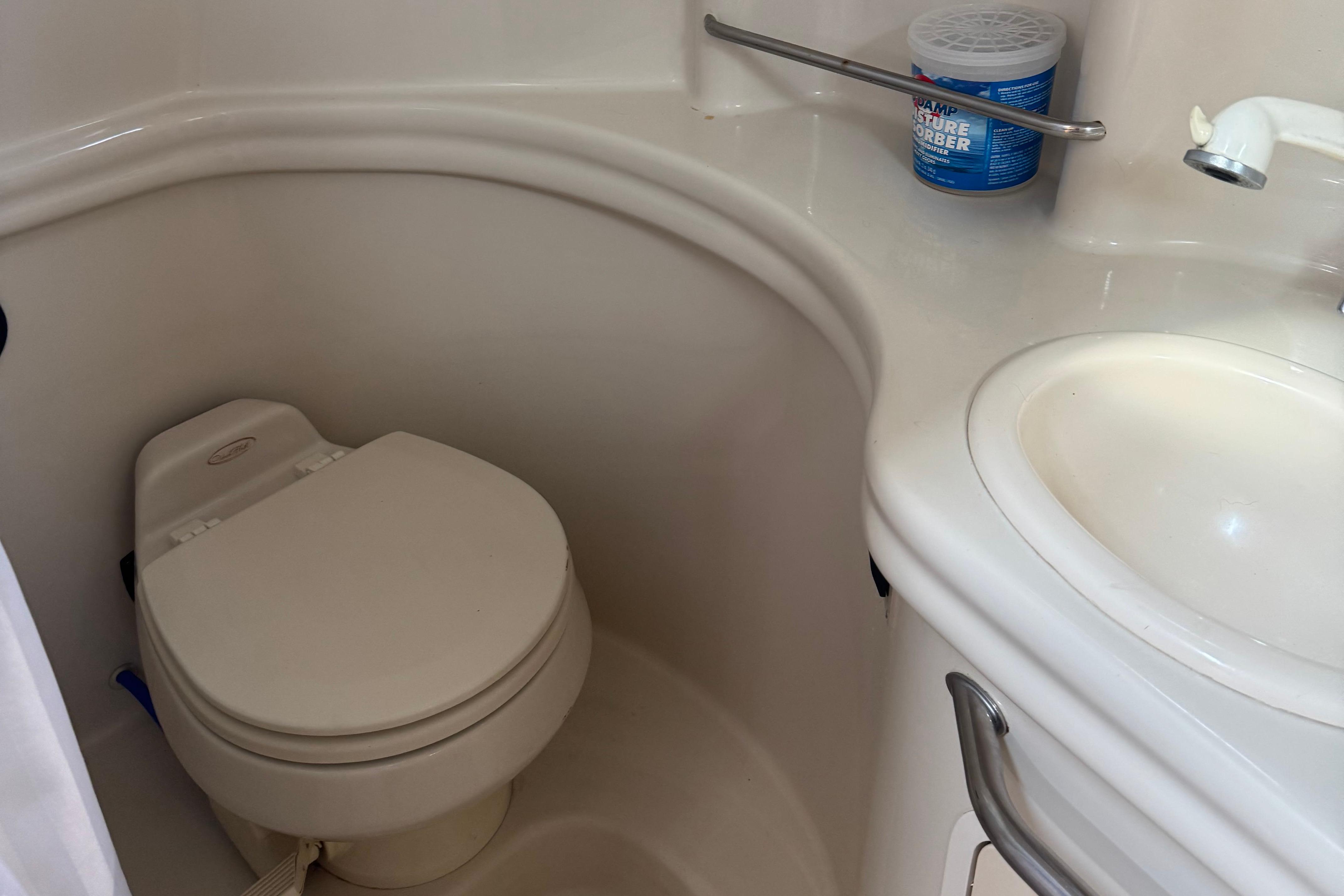 Compact bathroom in 2006 Sea Ray 300 Sundancer boat with toilet and sink.