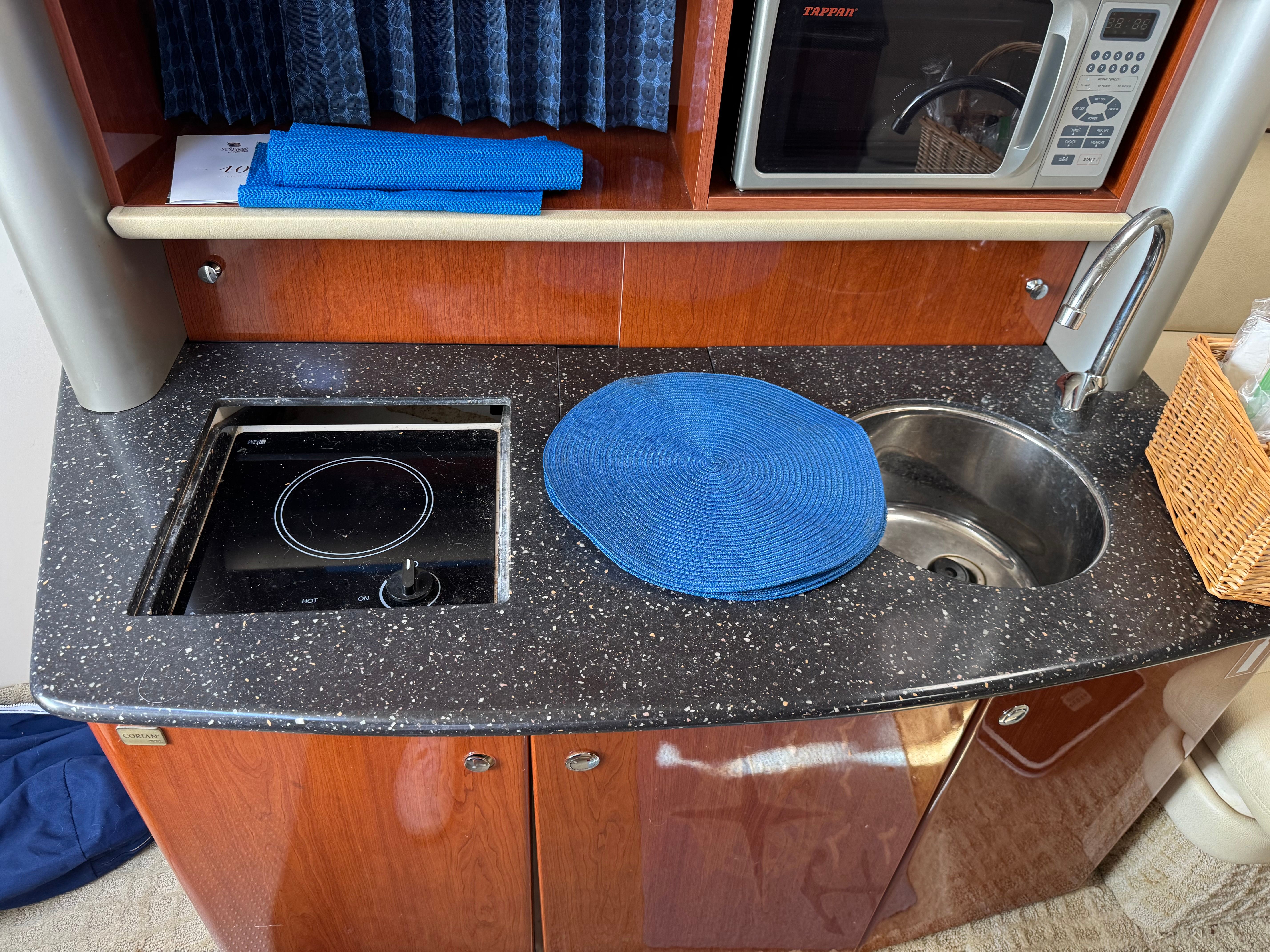 Galley with sink, stove, and microwave in a boat.