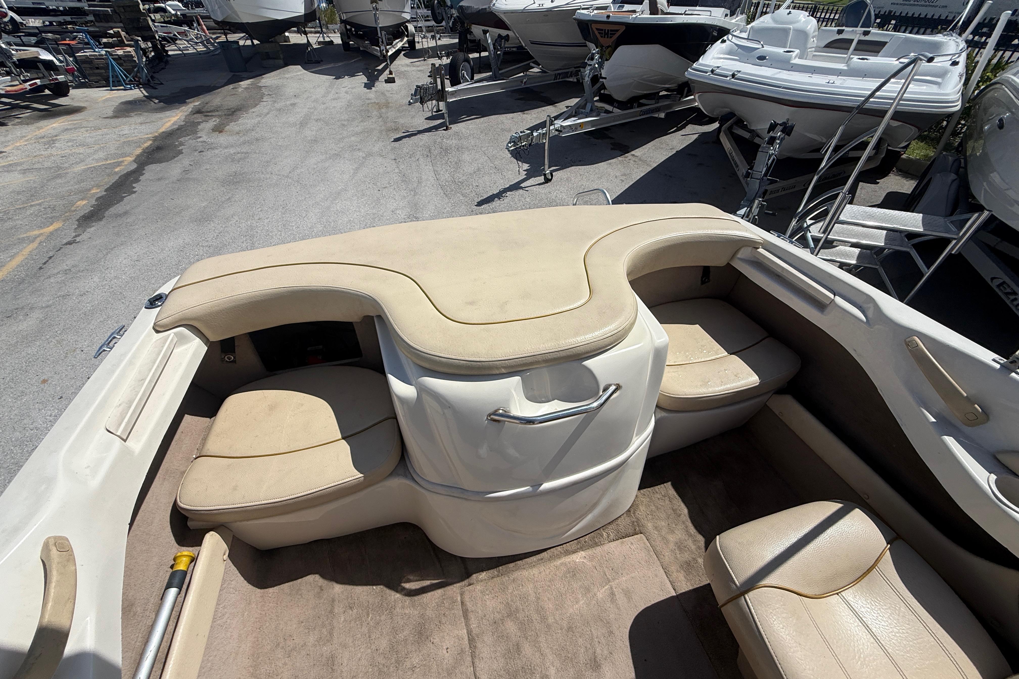 2001 Sea Ray 180 Bow Rider interior with beige seating, parked among other boats.